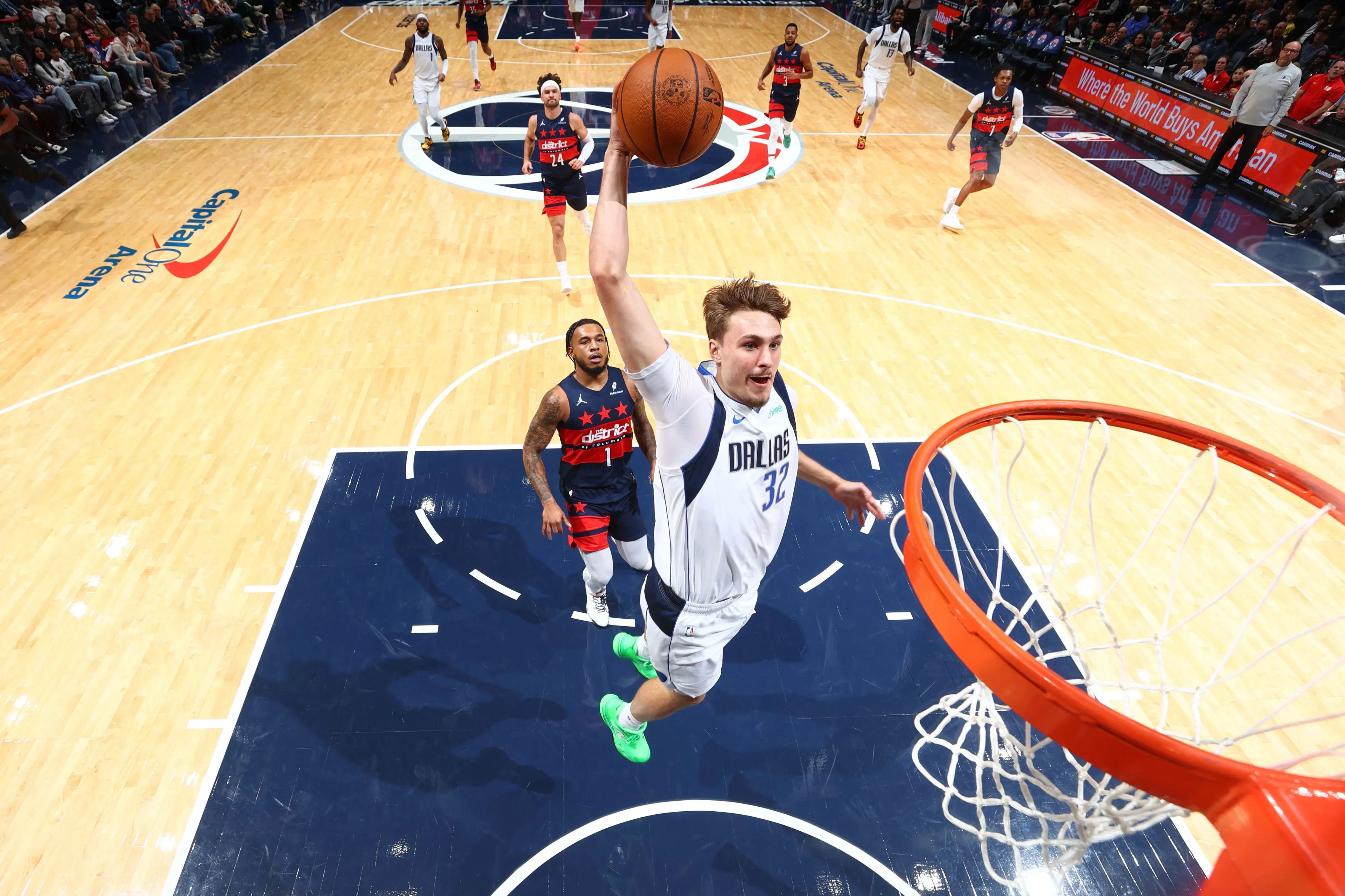 لاعب كرة سلة من فريق دالاس مافريكس يقوم بتسديد كرة في سلة الخصم خلال مباراة، مع وجود لاعبين آخرين في الخلفية.