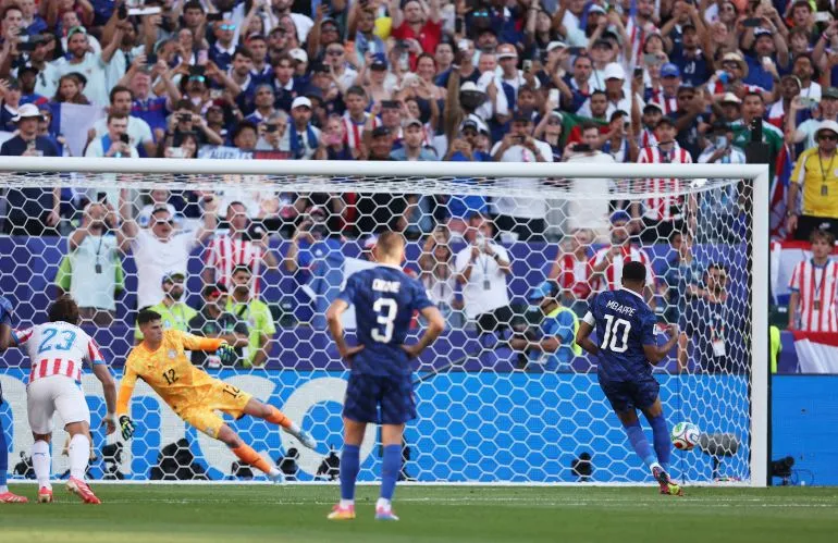كيليان مبابي يسدد ركلة جزاء حاسمة ضد باراغواي في دور الـ16 لكأس العالم، وسط أجواء مشحونة وحضور جماهيري كبير.