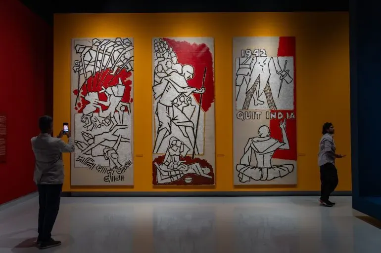 لوحات فنية لمقبول فدا حسين تعرض في متحف "لوح وقلم" بالدوحة، مع زوار يتفاعلون مع الأعمال التي تعكس التاريخ والثقافة.