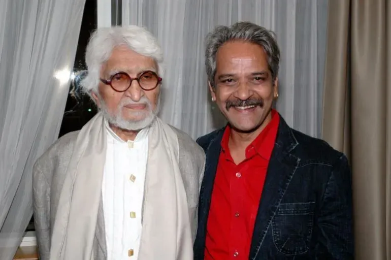 صورة لمقبول فدا حسين، الفنان الهندي الشهير، مع شخص آخر في حدث فني، يعكس تأثيره الثقافي وتاريخه الفني.