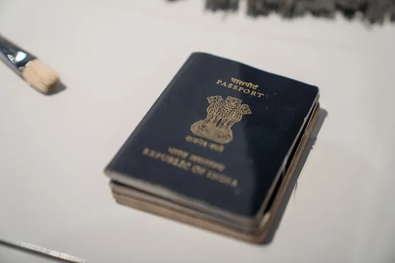 جواز سفر هندي قديم لمقبول فدا حسين، الفنان المعروف، مع فرشاة رسم، يعكس مسيرته الفنية وتأثيره الثقافي.