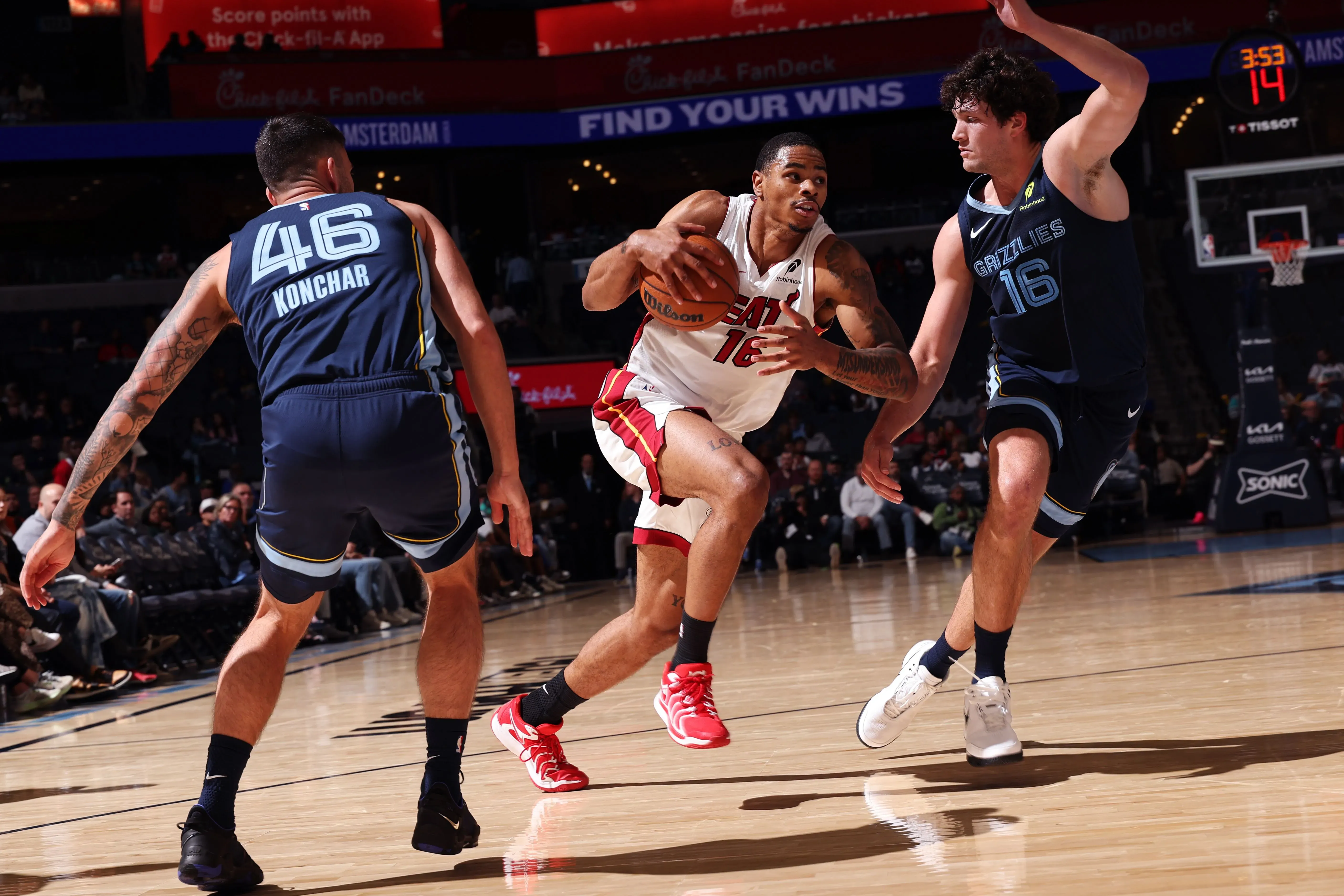 لاعب من فريق ميامي هيت يتجاوز مدافعين من فريق ممفيس جريزليز خلال مباراة كرة سلة، مع التركيز على الأداء في ظل ظروف صعبة.