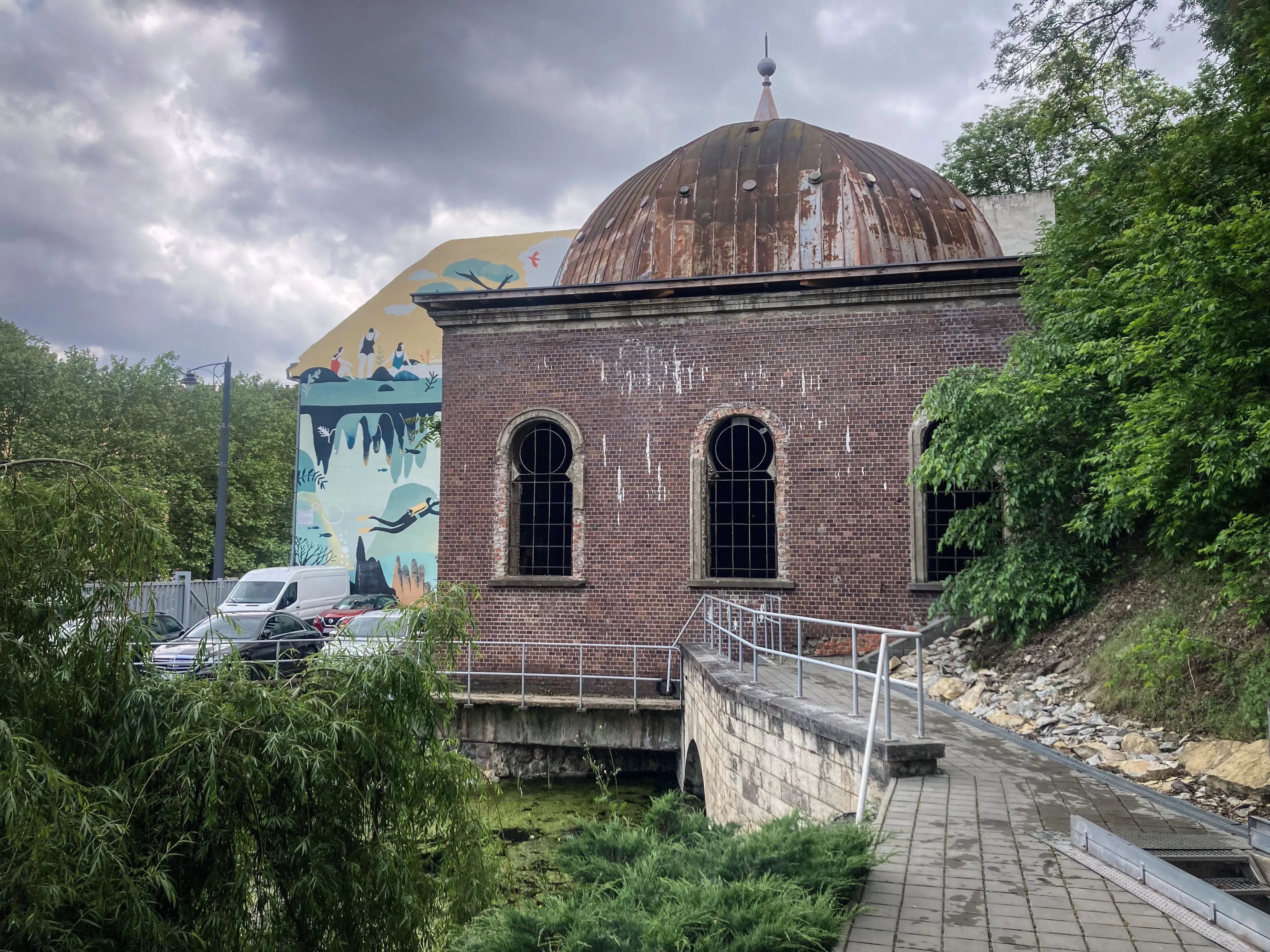 مدخل كهف مولنار يانوس في بودابست، بجوار مبنى قديم، مع جدارية لغواص، يرمز إلى عالم تحت الماء غني بالمعادن.