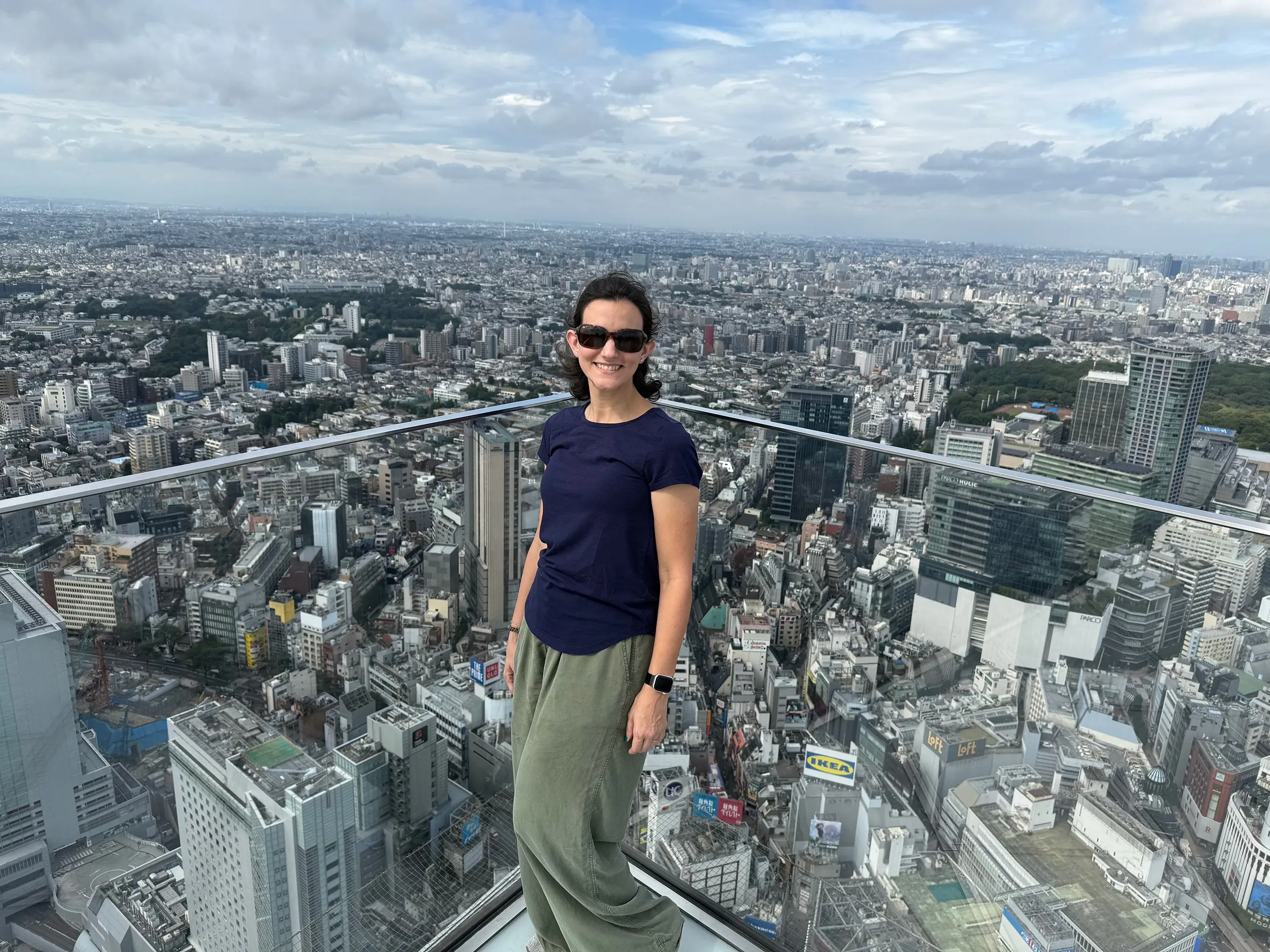 امرأة ترتدي نظارات شمسية وتقف على شرفة تطل على مدينة مزدحمة، تعكس أهمية الصحة القلبية والوقاية من الأمراض.