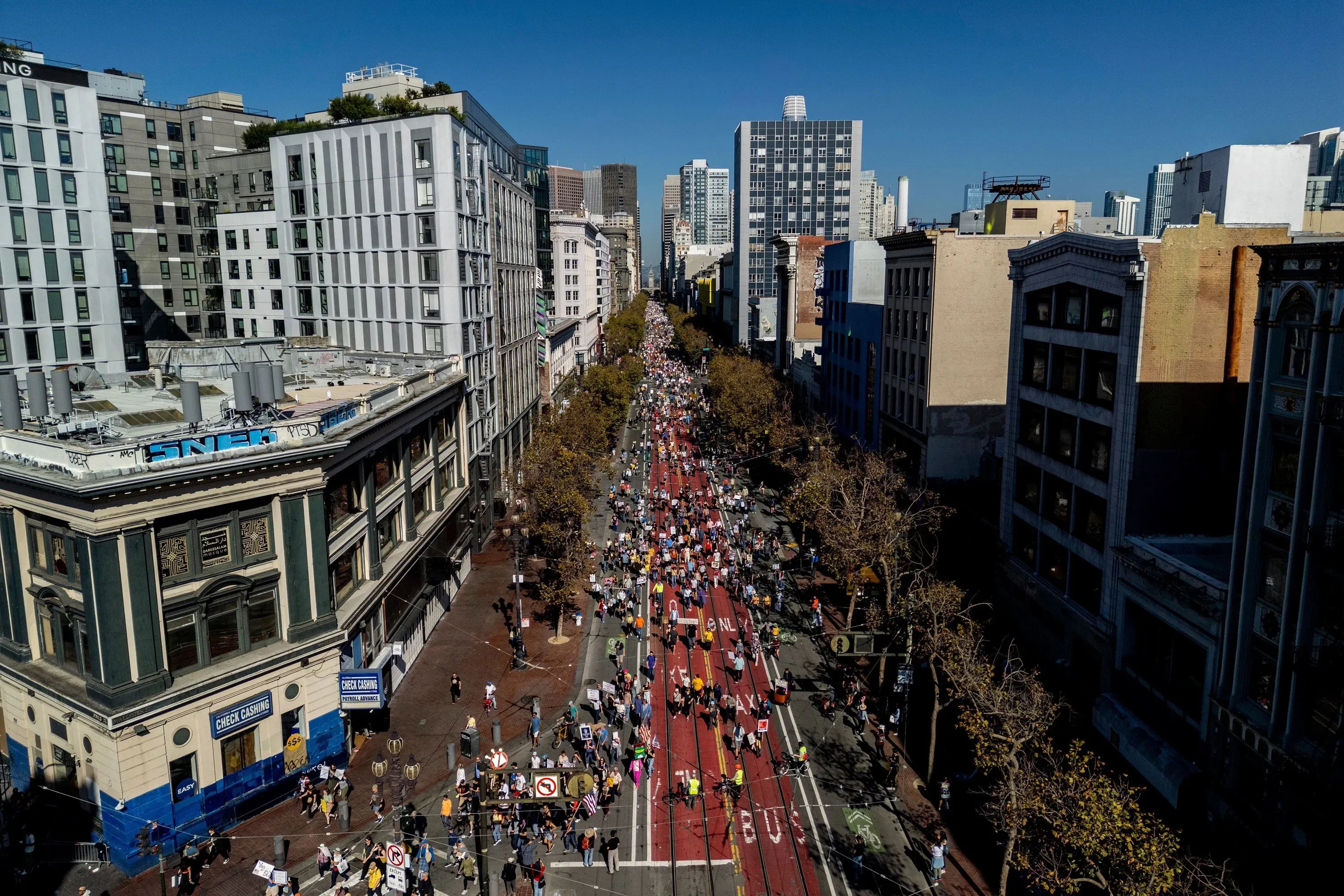 مظاهرة حاشدة في مدينة مزدحمة، حيث يسير الآلاف من المتظاهرين في الشوارع حاملين لافتات تعبر عن معارضتهم لسياسات ترامب.