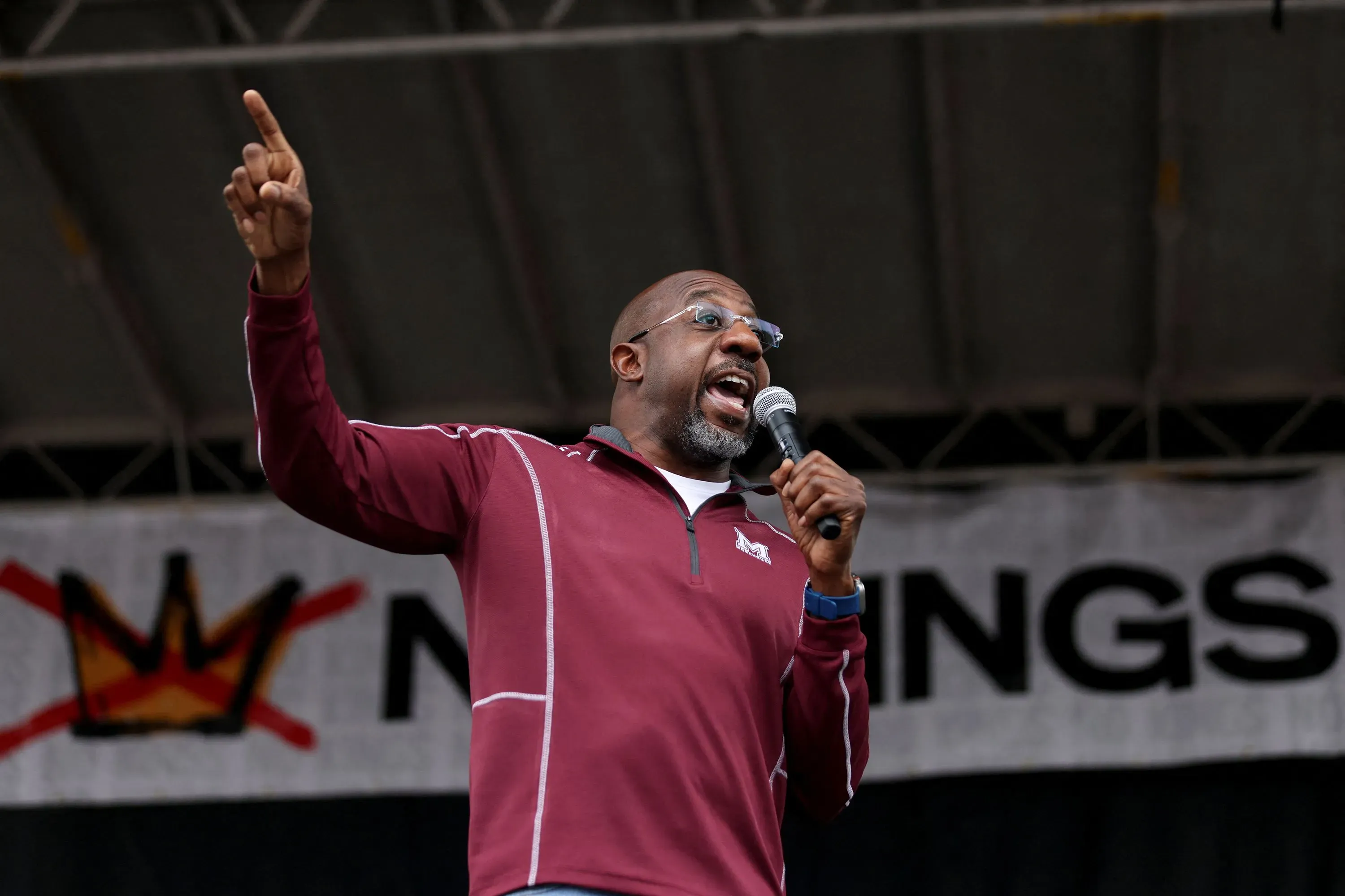 يتحدث متحدث بارز في مظاهرة "لا للملوك"، مع وجود لافتة كبيرة خلفه. تعكس الفعالية روح المقاومة والدفاع عن الديمقراطية.