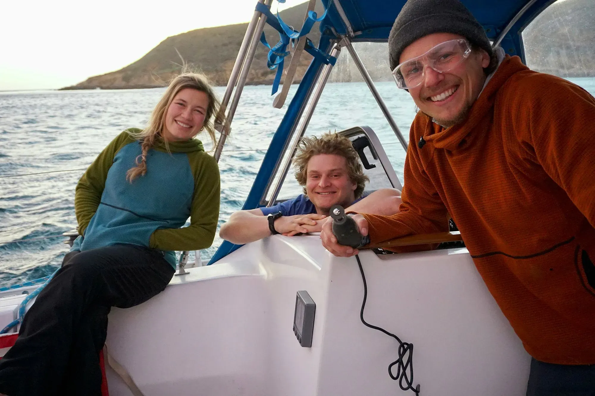 مجموعة من الأصدقاء في العشرينات من عمرهم يستمتعون بالإبحار على متن قارب شراعي، مع خلفية بحرية وسماء مفتوحة، تعبيراً عن مغامرتهم في المحيط.