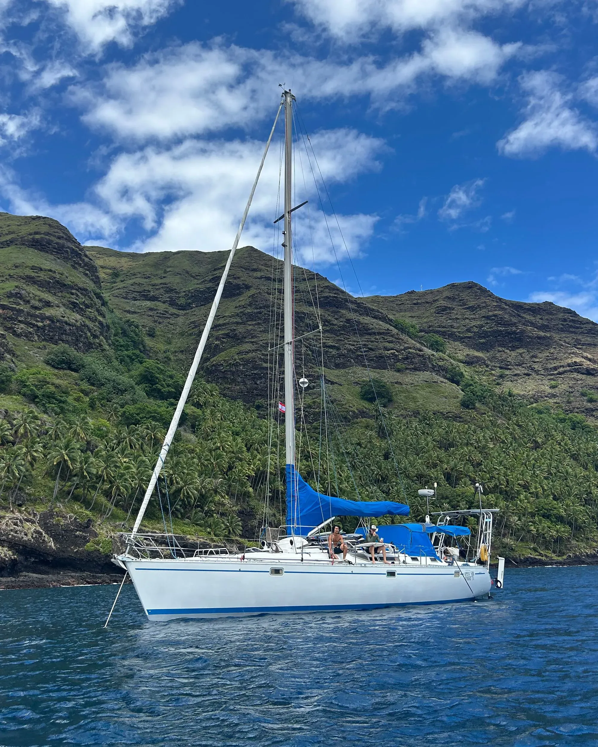 يظهر القارب الشراعي الأبيض مع أشرعة زرقاء يرسو بالقرب من الجزر الخضراء في بولينيزيا الفرنسية، حيث يستمتع مجموعة من الأصدقاء برحلة بحرية مغامرة.