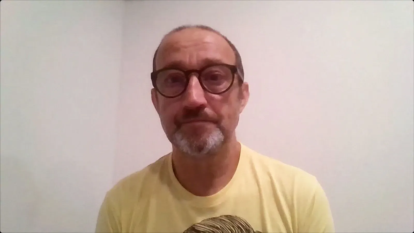 شخص بالغ يرتدي نظارات وقميص أصفر، يظهر تعبير الحزن والقلق. الصورة تعكس مشاعر المجتمع بعد حادث إطلاق النار في مينيابوليس.