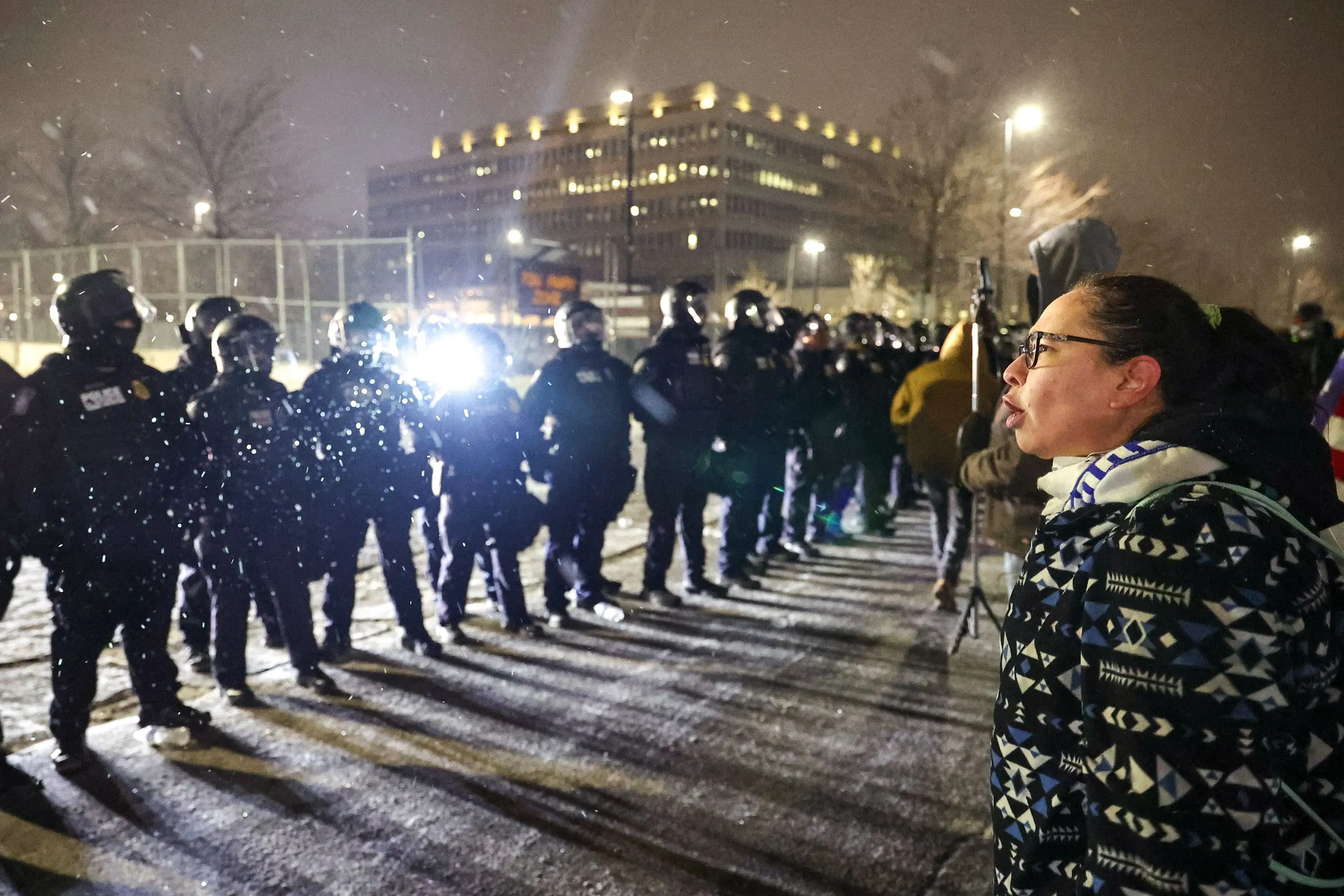 محتج يتحدث إلى قوات الشرطة في مينيابوليس خلال مظاهرة في أجواء ثلجية، وسط تعزيزات أمنية لدعم الاحتجاجات السلمية.