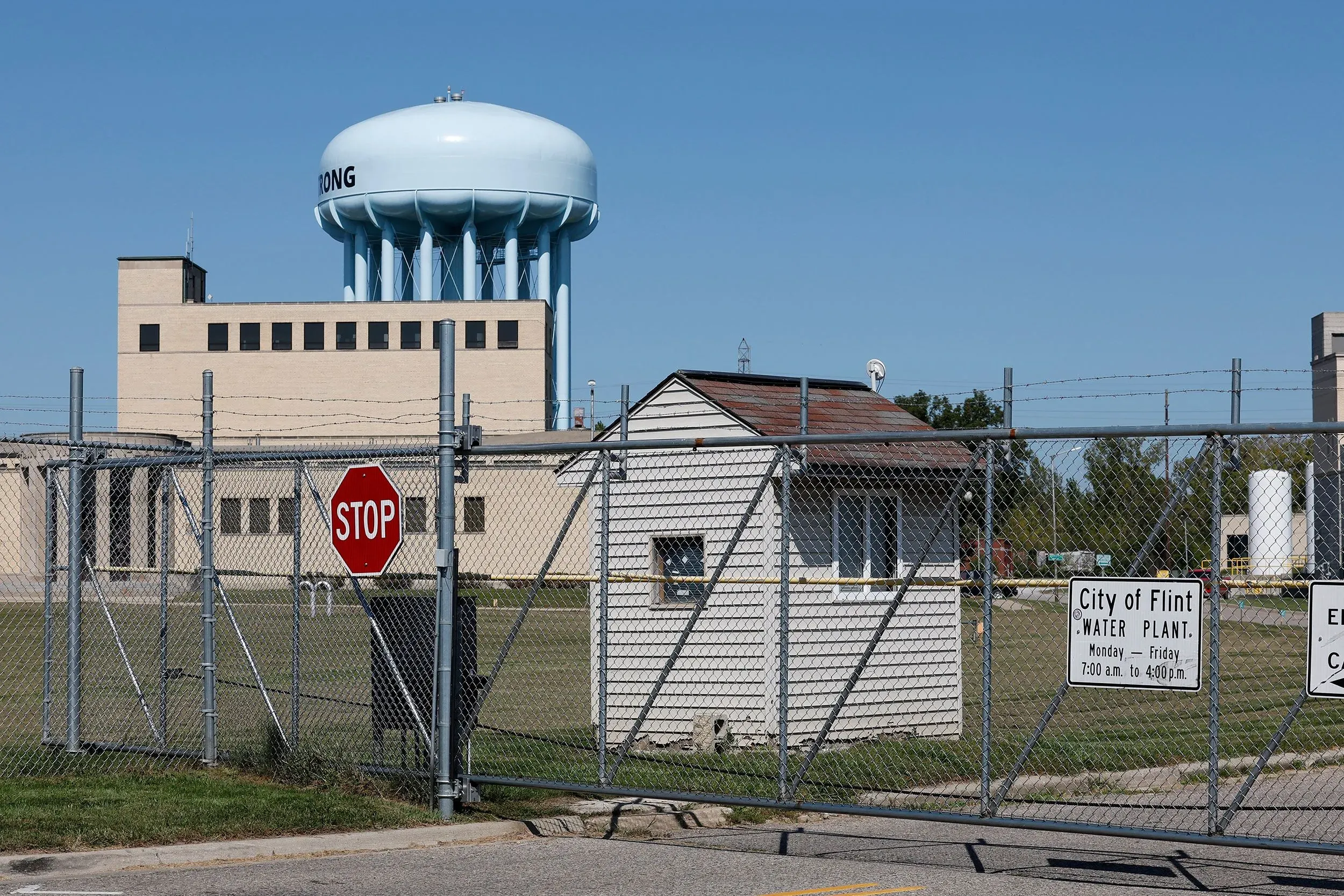 صورة لمصنع مياه مدينة فلينت بولاية ميشيغان، يظهر خزان المياه ومرافق محاطة بسياج. تعكس الصورة أزمة المياه المستمرة في المنطقة.