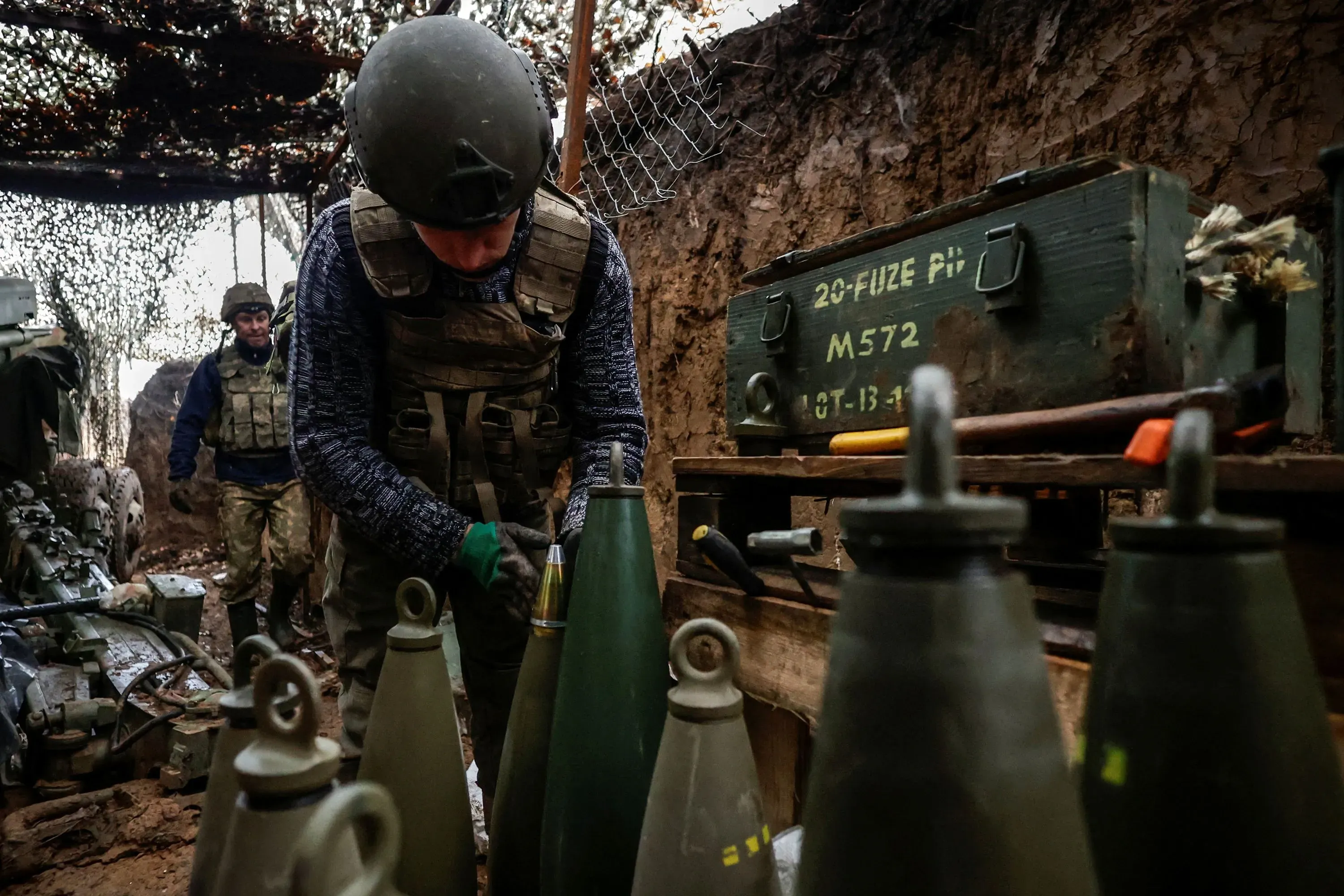 جنود أوكرانيون في موقع عسكري يقومون بتحضير الذخيرة، مع وجود صناديق ذخيرة وأسلحة في الخلفية، في سياق التصعيد العسكري في أوكرانيا.