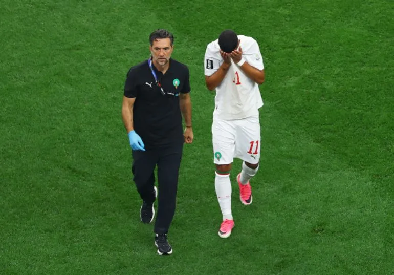المدرب محمد وهبي يرافق لاعب المغرب إسماعيل صيباري المصاب أثناء مباراة كأس العالم قبل مواجهة فرنسا في ربع النهائي.