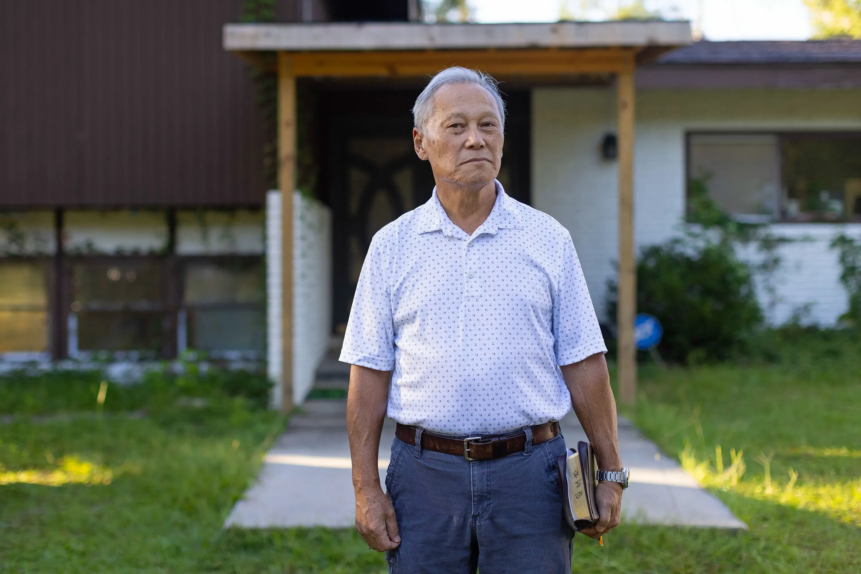 رجل مسن يقف أمام منزله في إيلابيل، جورجيا، مع تعبير جاد، بينما تعكس الخلفية تأثير الغارة الأمنية على المجتمع المحلي.