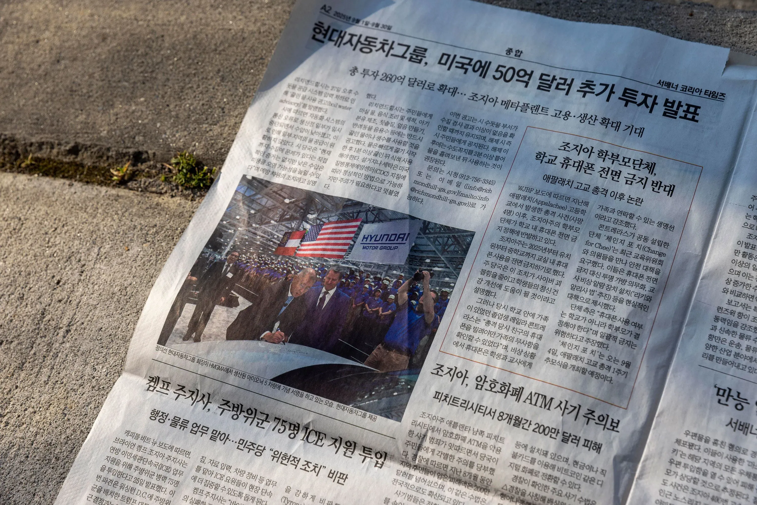 صورة لجريدة تتضمن خبرًا عن استثمار هيونداي في الولايات المتحدة، مع ظهور علمي الولايات المتحدة وكوريا الجنوبية في الخلفية.