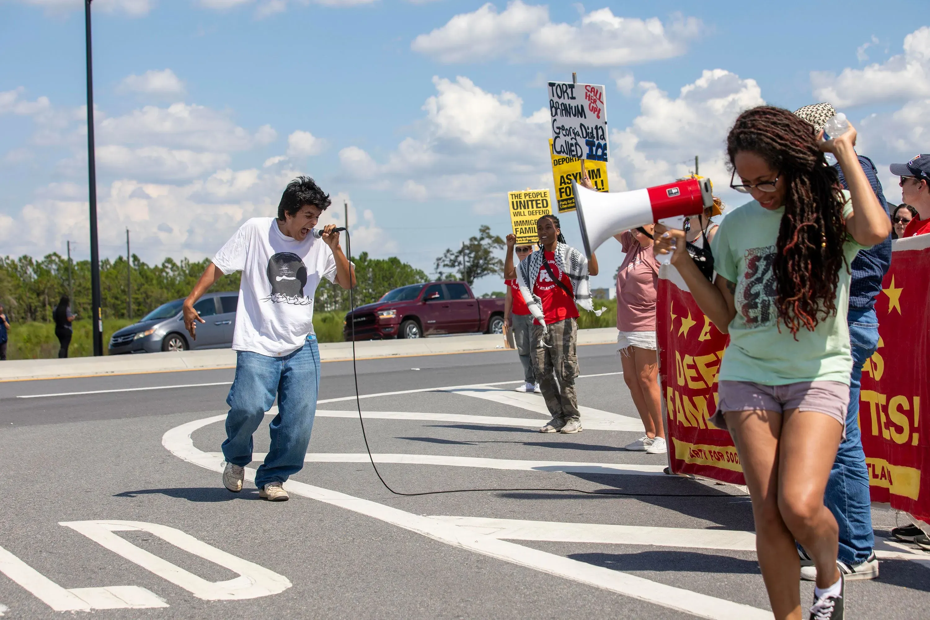 محتجون في إيلابيل، جورجيا، يحملون لافتات ويستخدمون مكبر صوت للتعبير عن مطالبهم، بينما يتظاهرون ضد مداهمة الهجرة التي استهدفت عمال مصنع هيونداي.