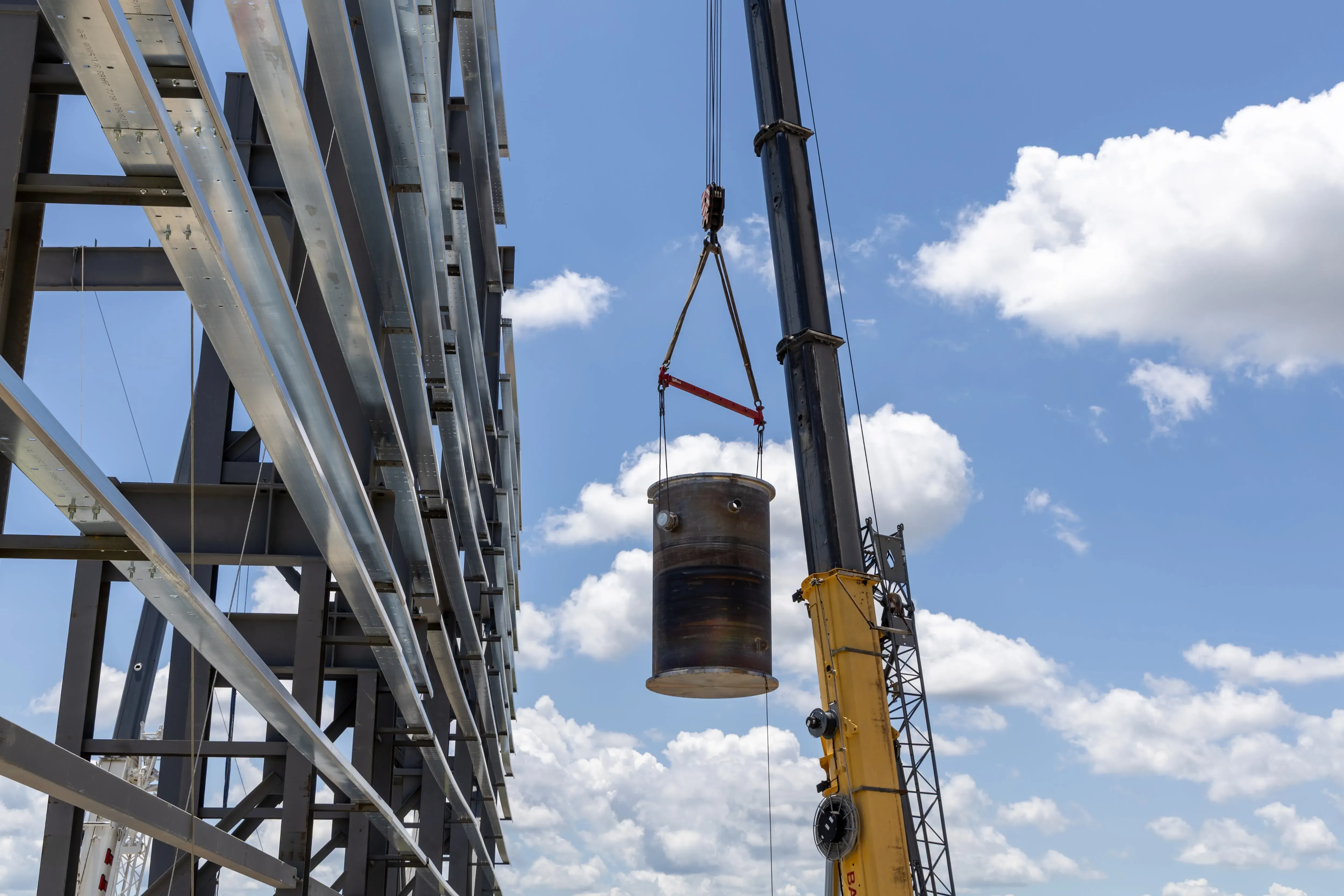 رفع رافعة لمفاعل نووي صغير في موقع بناء، مع سماء زرقاء وصحوة، مما يعكس جهود إعادة تشغيل محطة باليسيدس النووية في ميشيغان.