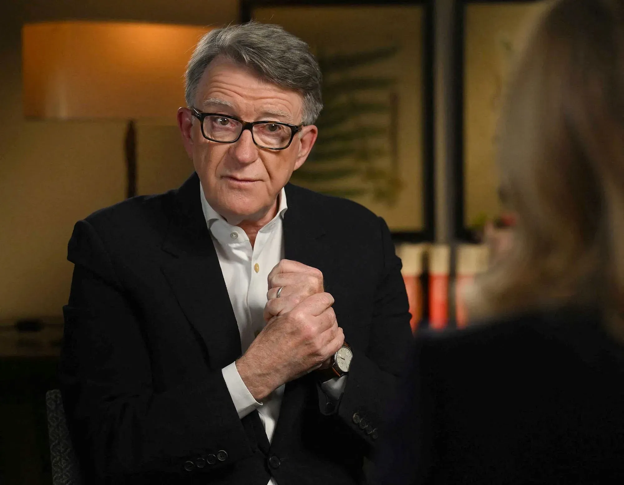 رجل في بدلة سوداء يجلس في مقابلة، يعبر عن مشاعر القلق حول قضايا جيفري إبشتاين وتأثيرها على الضحايا.