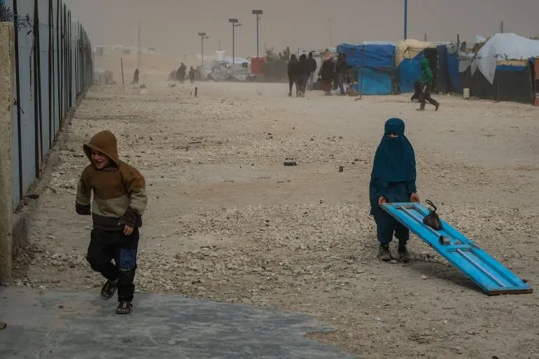 طفلان يلعبان في مخيم للاجئين بسوريا، حيث تظهر الظروف القاسية والمناخ الصعب في المنطقة.