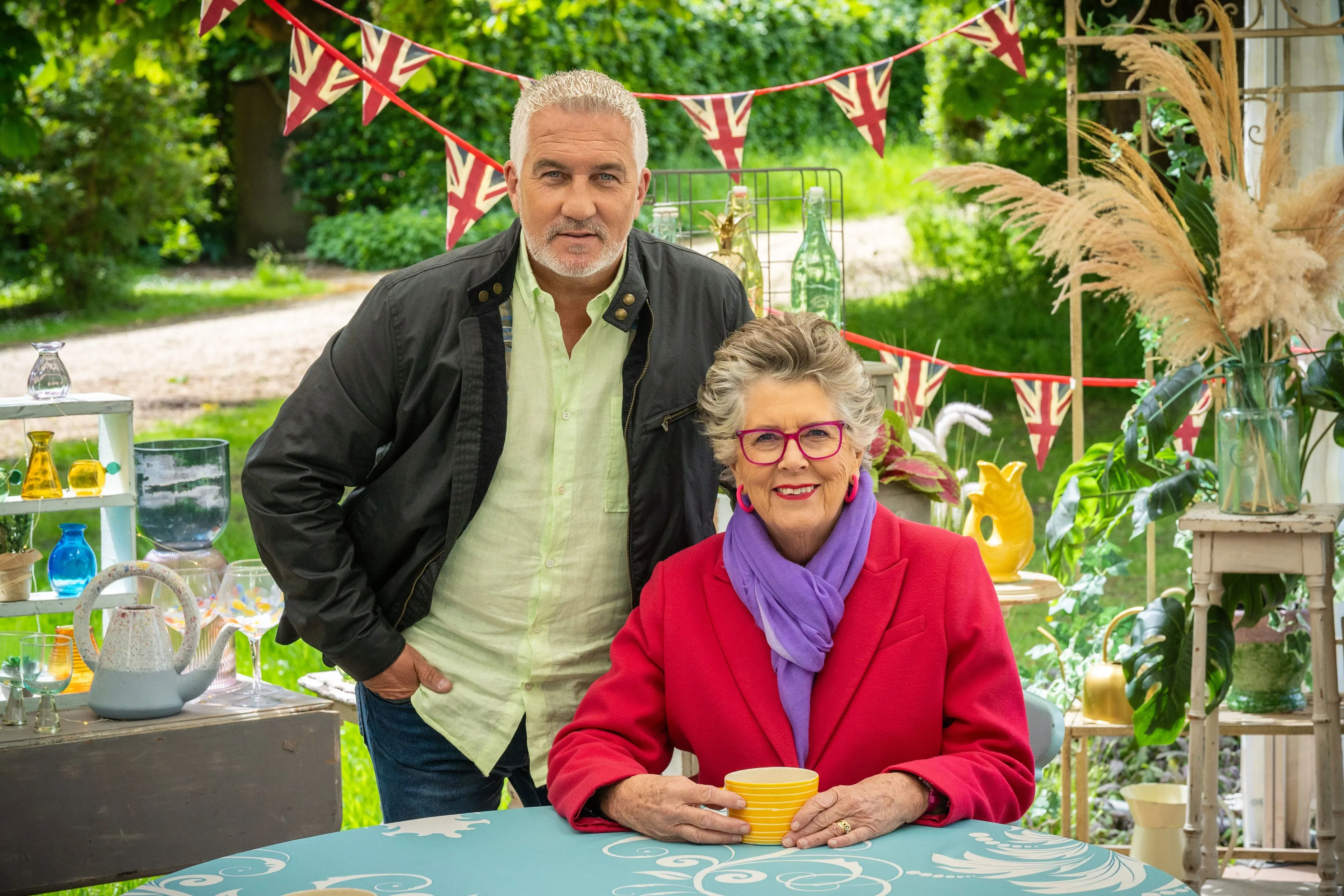 انضمام نايجيلا لوسون إلى لجنة تحكيم برنامج "The Great British Baking Show"، مع وجود بول هوليوود في الخلفية.