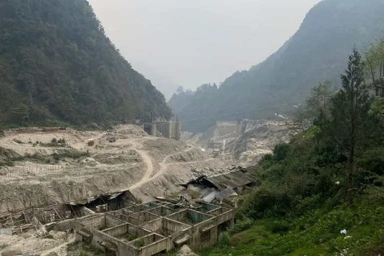 مشهد من قرية ناغا في سيكيم، يظهر الدمار الناتج عن الفيضان، مع منازل مدمرة وأرض مغطاة بالأنقاض، وسط جبال خضراء.