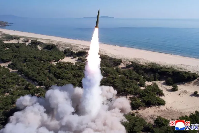إطلاق صاروخ باليستي قصير المدى من كوريا الشمالية نحو بحر الشرق، مع تصاعد الدخان والنار من منصة الإطلاق.