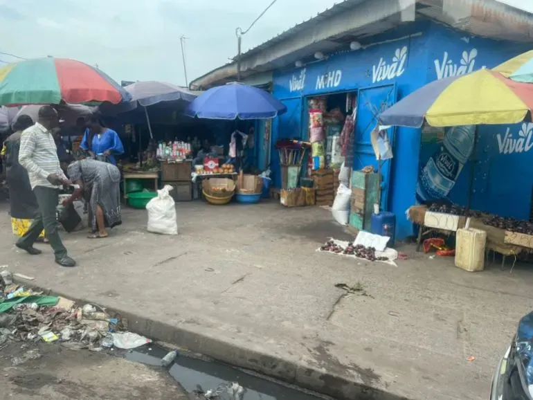 سوق موكوندو في برازافيل، حيث تتجمع الناس تحت المظلات الملونة، مع بائعات يحاولن جذب الزبائن وسط أجواء انتخابية مشحونة.