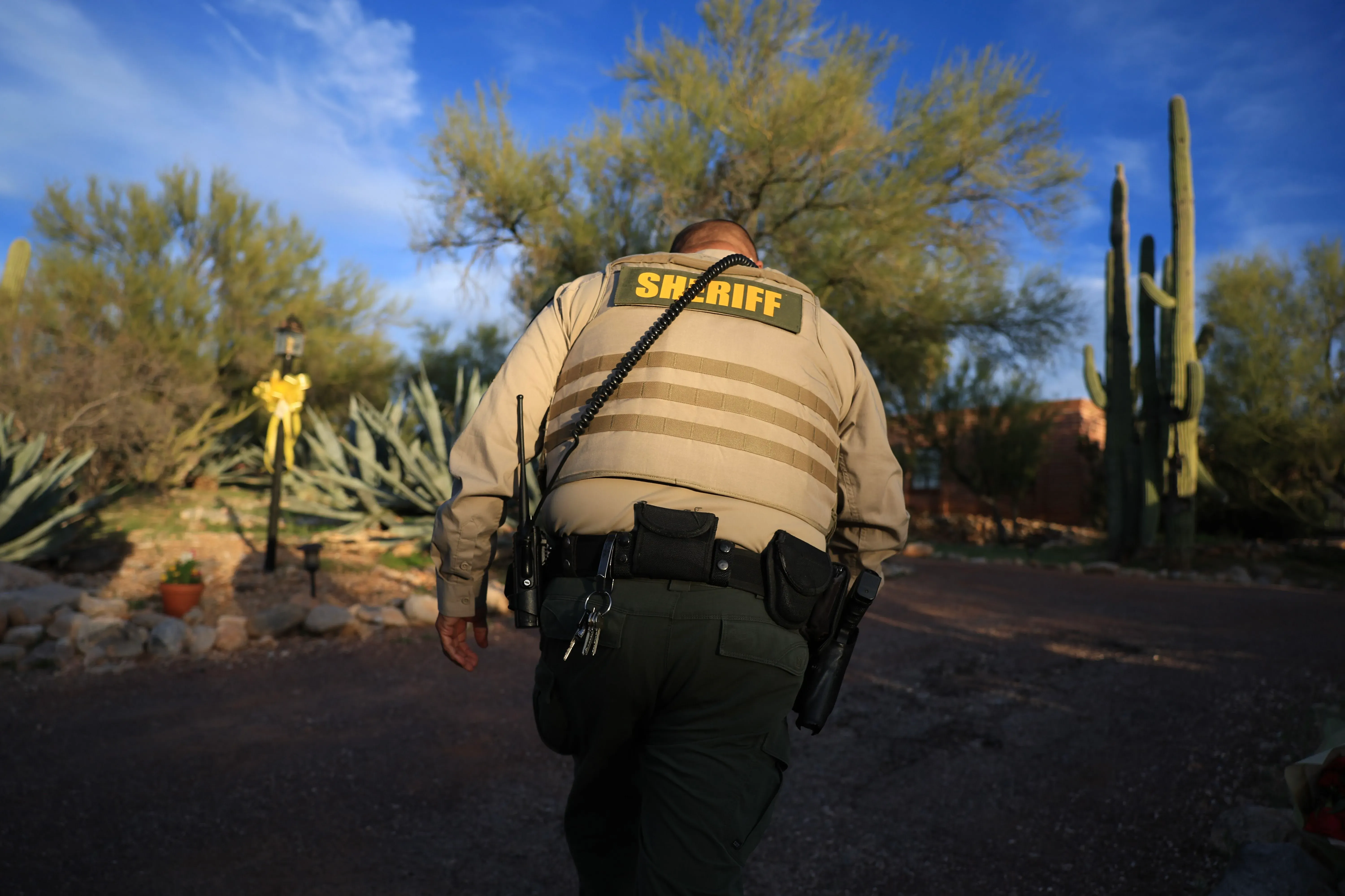 شرطي يسير في منطقة صحراوية بأريزونا، محاط بأشجار الصبار، خلال التحقيق في اختفاء نانسي غوثري.