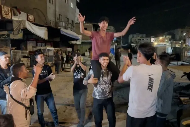 شبان فلسطينيون يحتفلون في شوارع خان يونس بعد إعلان اتفاق وقف إطلاق النار، معبرين عن فرحتهم بإنهاء العنف في غزة.