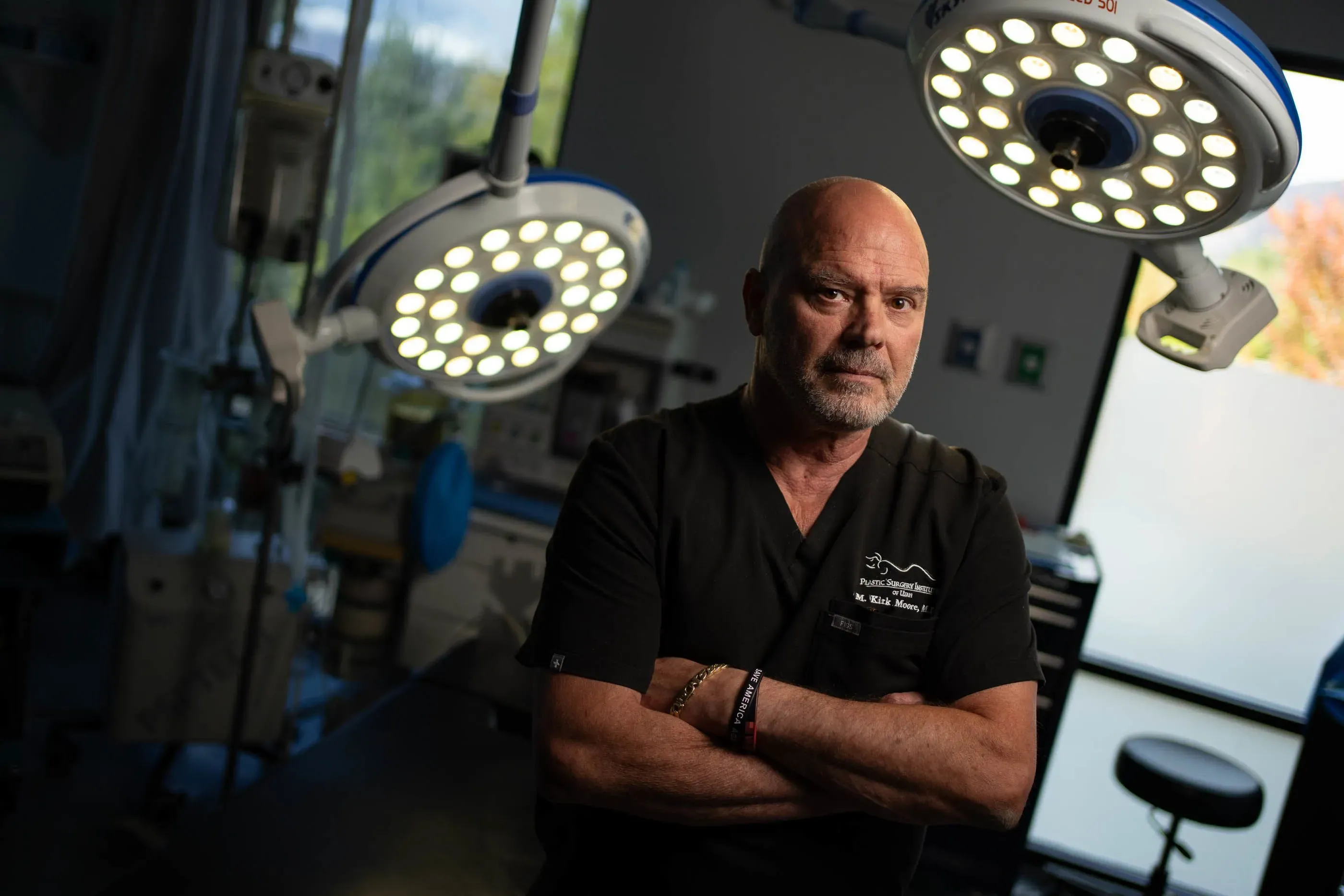 الدكتور كيرك مور، جراح تجميل، يقف في غرفة العمليات مع إضاءة جراحية خلفه، بعد تبرئته من تهم تزوير بطاقات لقاح كوفيد-19.