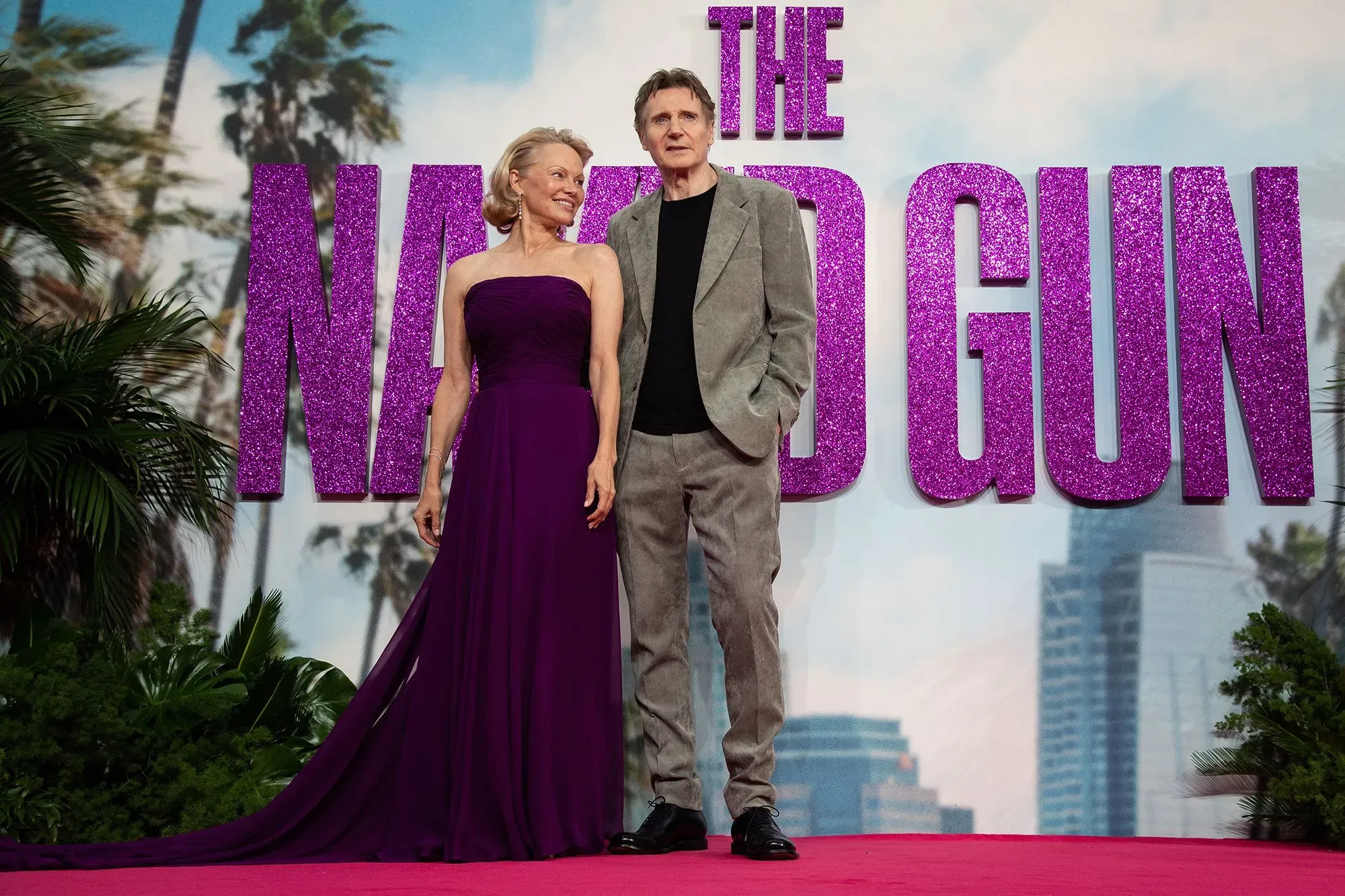 باميلا أندرسون وليام نيسون يقفان معًا في عرض فيلم "المسدس العاري"، حيث تعكس إطلالتهما الكيمياء بينهما.