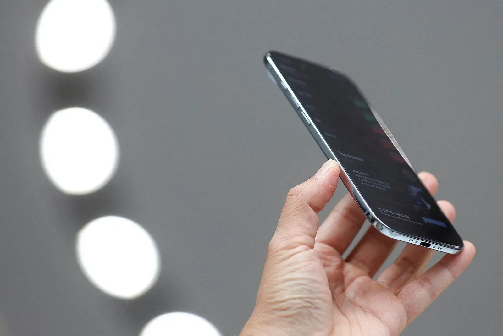 تصميم هاتف iPhone Air الجديد يظهر في يد شخص، مع التركيز على نحافته وشاشته، وسط خلفية غير واضحة.