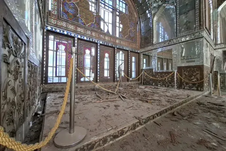 قصر كلستان المحطم يظهر آثار الدمار، مع شظايا الزجاج والأرضية المغطاة بالغبار، مما يعكس تأثير الحرب على التراث الثقافي الإيراني.