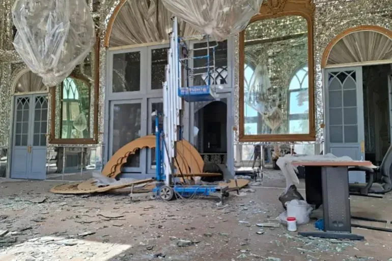 تظهر القاعة المدمرة في قصر كلستان، مع شظايا الزجاج والأعمال الحجرية المتضررة، مما يعكس آثار الحرب على التراث الثقافي الإيراني.