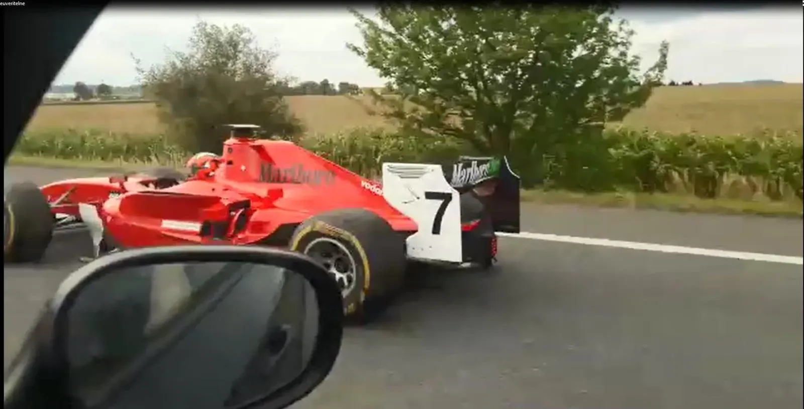 سيارة سباق حمراء على شكل فورمولا واحد تسير على الطريق السريع في جمهورية التشيك، مع مشهد طبيعي في الخلفية.