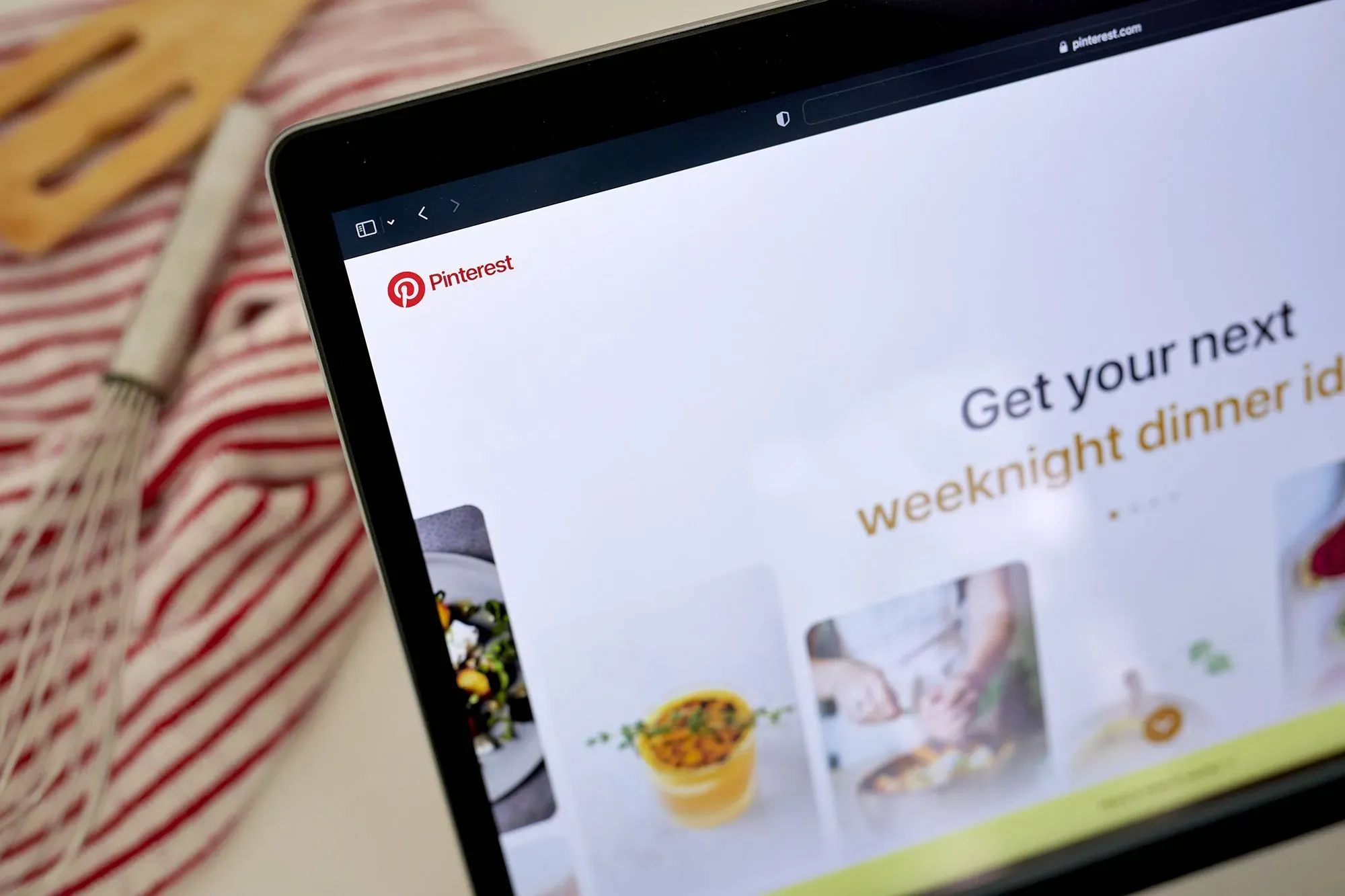 شاشة كمبيوتر تعرض موقع Pinterest مع نص يشجع المستخدمين على الحصول على أفكار لوجبات العشاء، محاطة بصور ملهمة للطعام.
