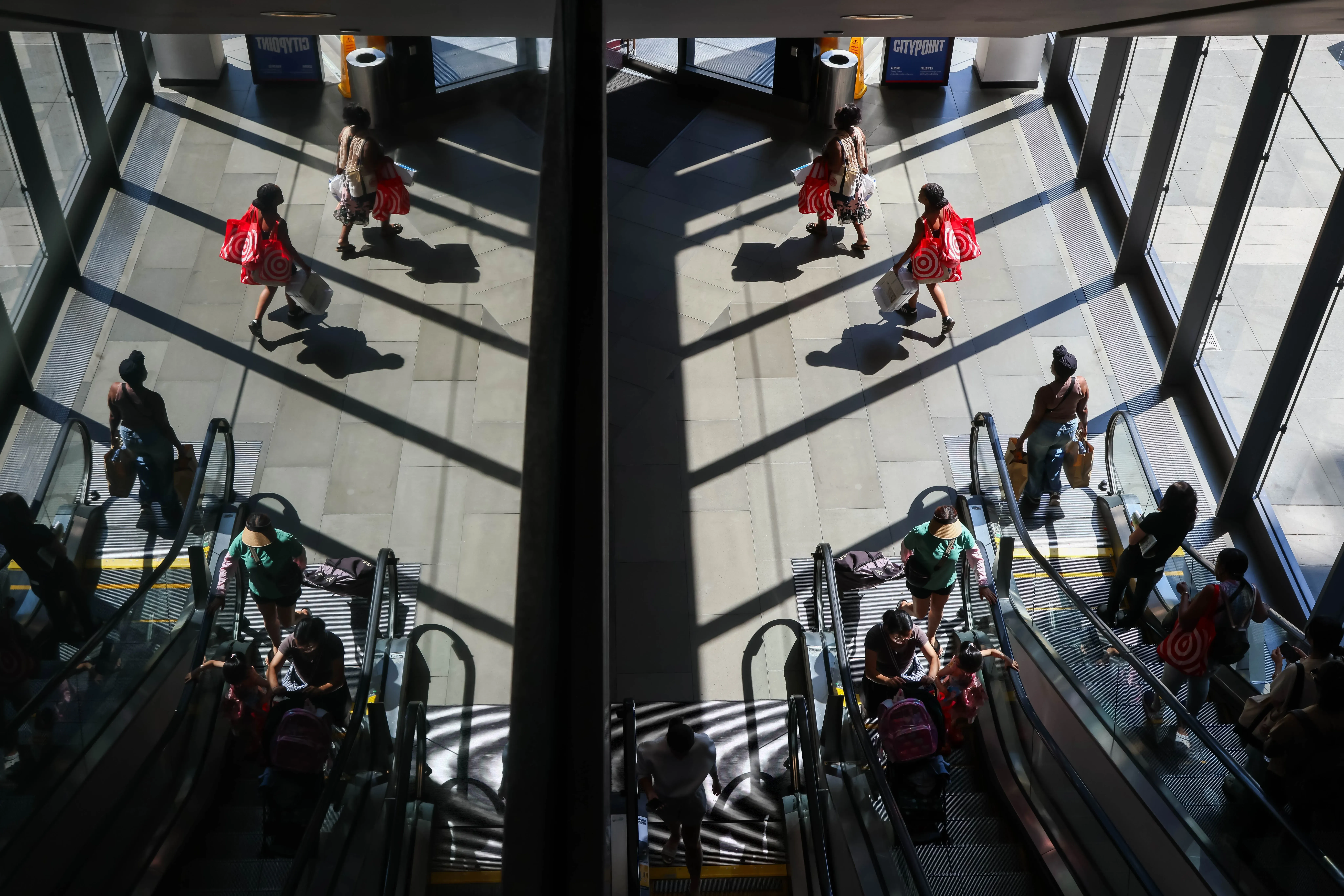 مشهد لمتسوقين يستخدمون السلالم المتحركة في مركز تجاري، مع وجود أكياس تسوق من متجر تارغت، يعكس تراجع خيارات الملابس ذات المقاسات الكبيرة.