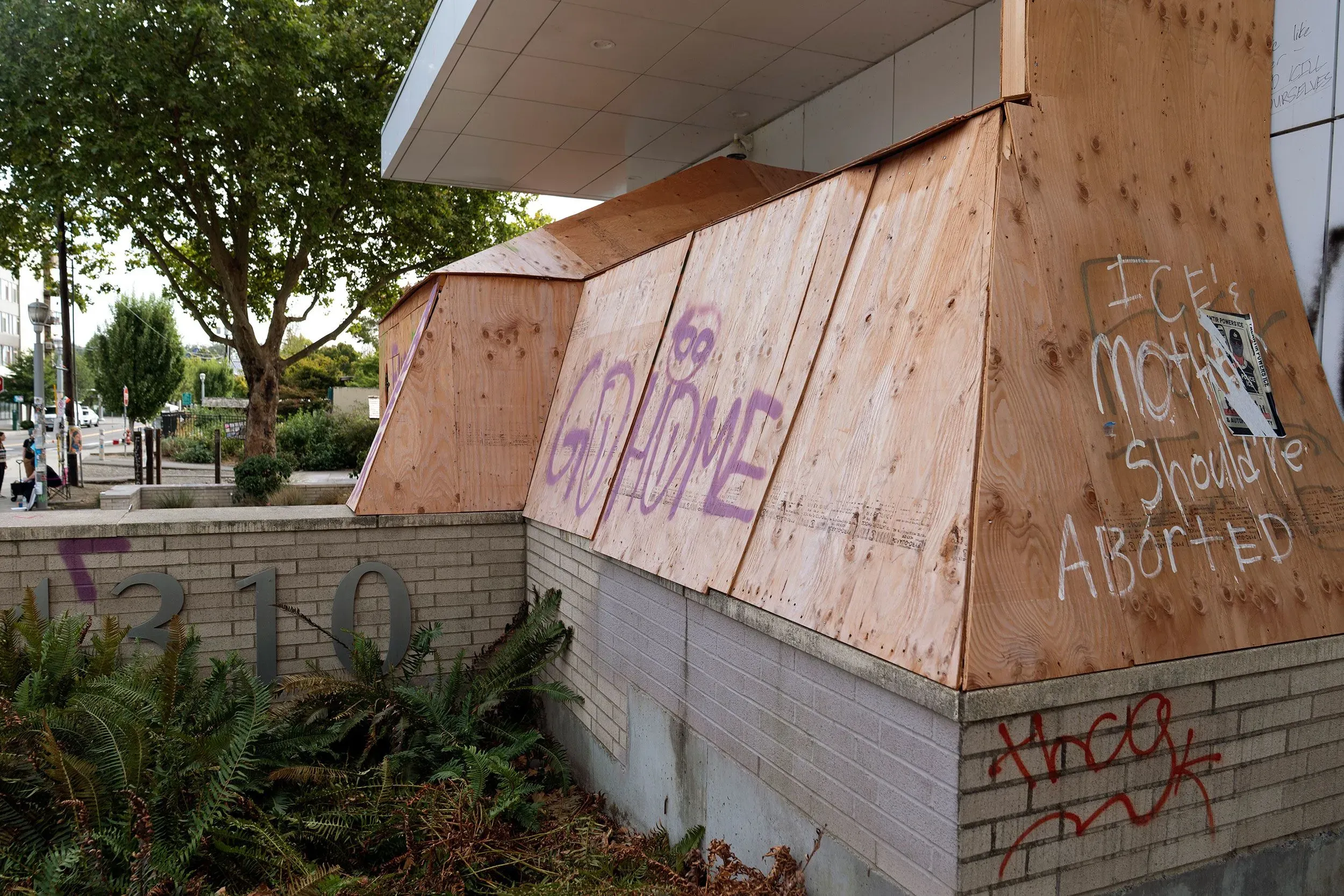 واجهة مبنى مغلقة بألواح خشبية، مع رسومات جدارية تعبر عن الاحتجاجات في بورتلاند، تعكس التوترات السياسية والاجتماعية الحالية.