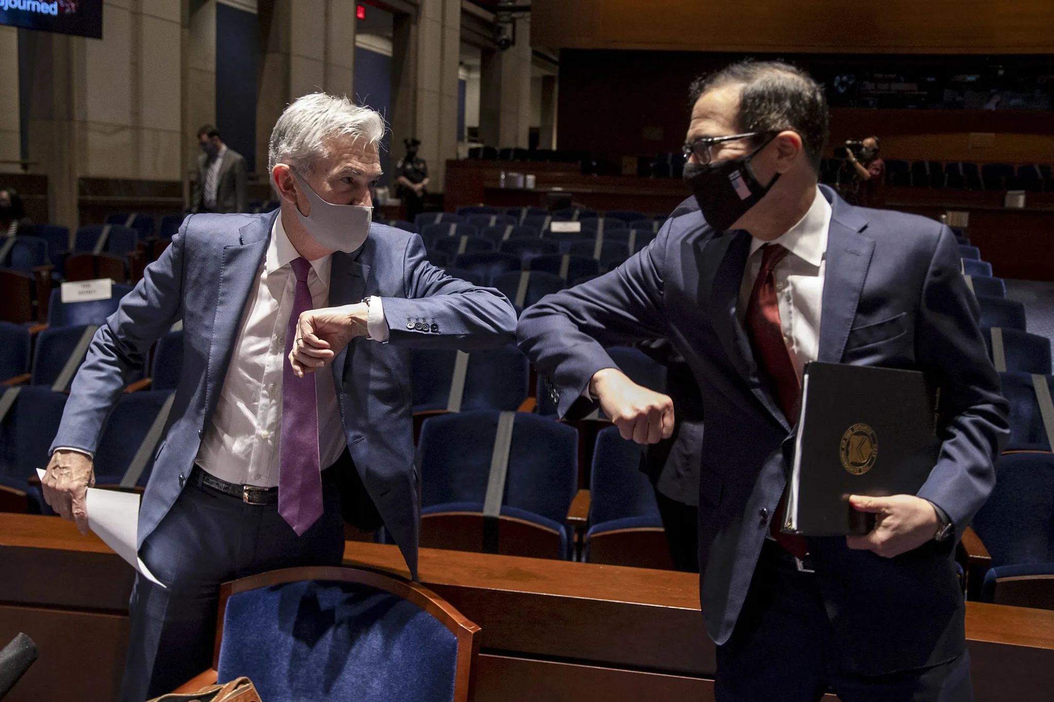تبادل Jerome Powell وKevin Warsh التحية في جلسة رسمية، مع ارتداء كليهما للكمامات، في سياق مناقشات حول السياسة النقدية.