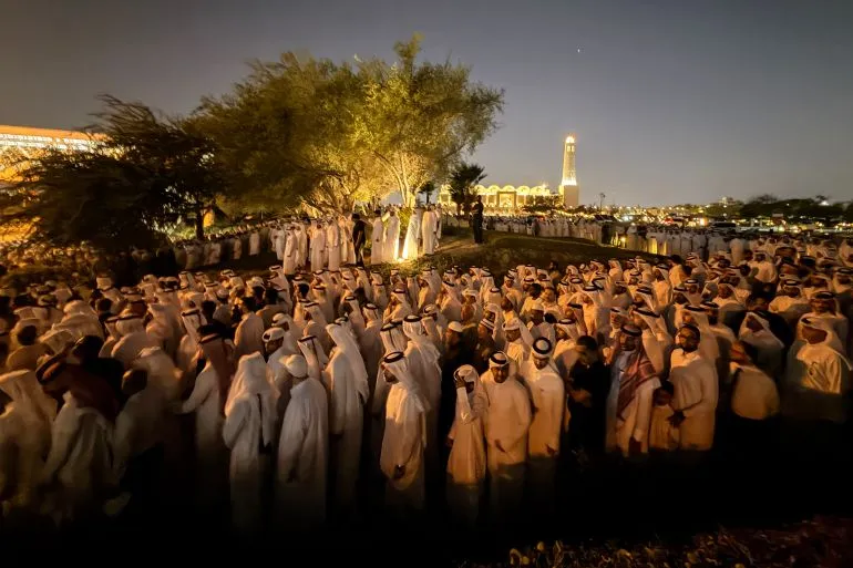 مشيعون يرتدون الزي القطري التقليدي يؤدون صلاة الجنازة في مقبرة لوسيل بالدوحة لوداع الشيخ حمد بن خليفة آل ثاني، مؤسس نهضة قطر الاقتصادية والسياسية.