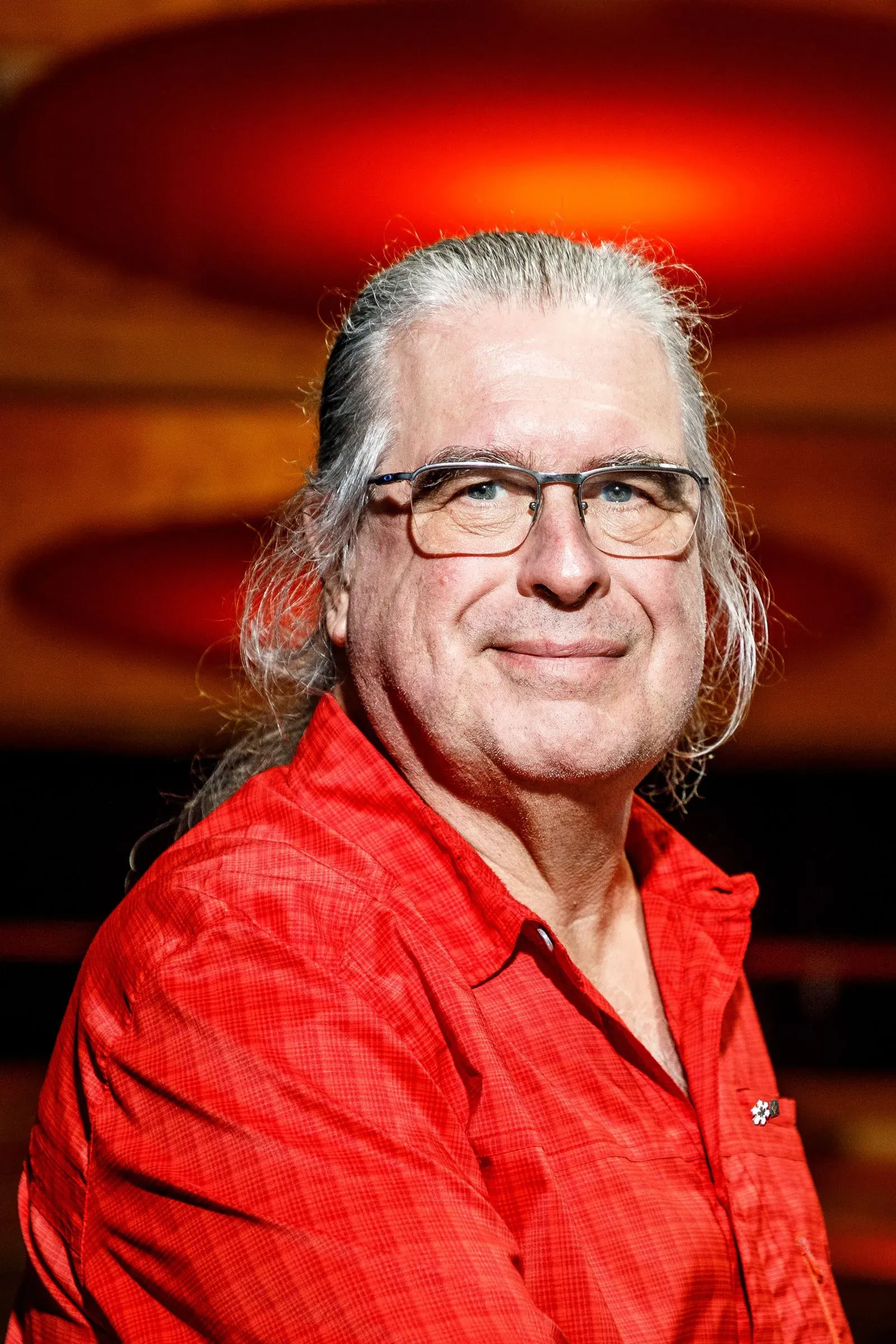 صورة لعالم الفيزياء تشارلز بينيت مبتسمًا، يرتدي قميصًا أحمر، مع خلفية دافئة. يُعرف بمساهماته في التشفير الكمي.