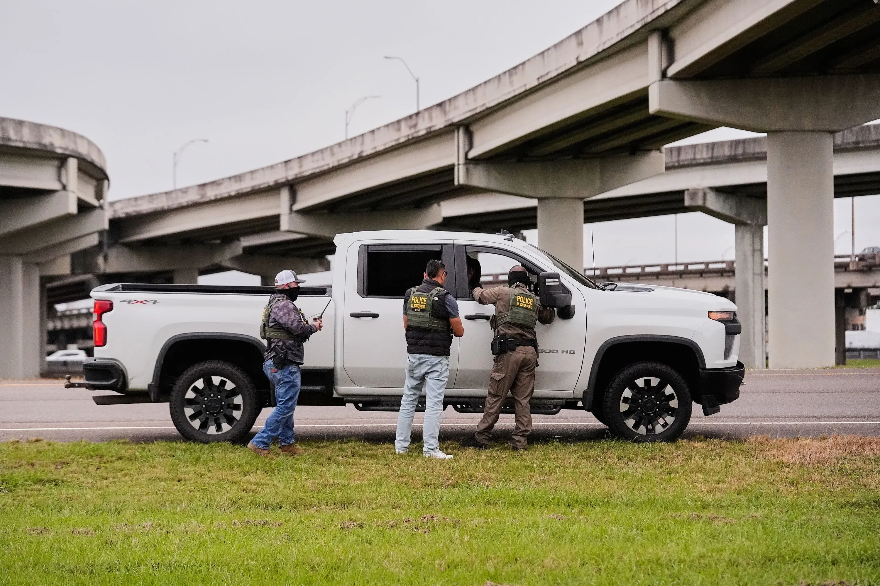 أفراد من قوات إنفاذ القانون يتحدثون مع سائق في سيارة بيك آب تحت جسر في نيو أورليانز، وسط إجراءات مراقبة تتعلق بحملة الهجرة.