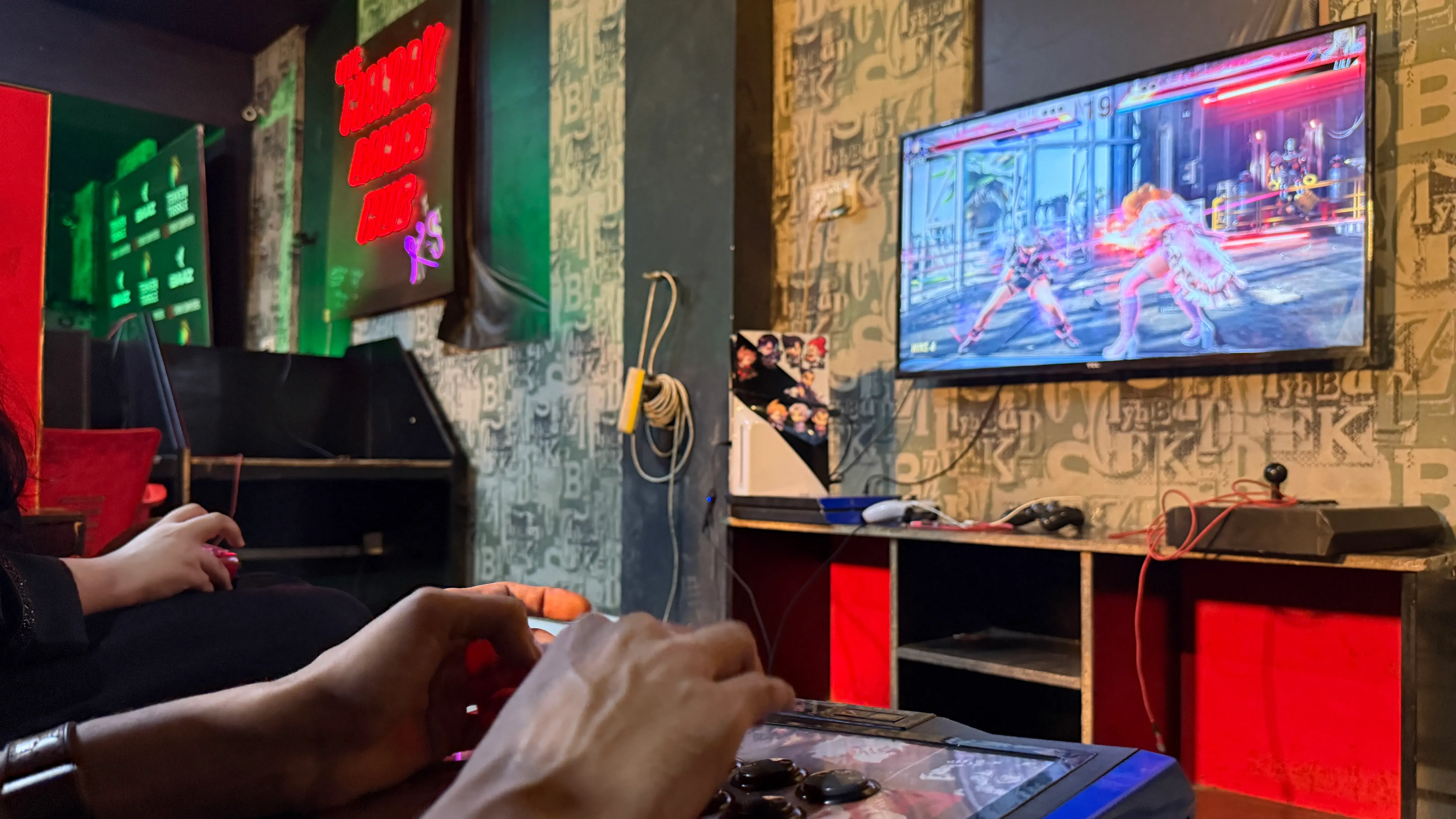 شخصان يلعبان لعبة Tekken في صالة ألعاب في لاهور، مع شاشة تعرض معركة حماسية، مما يعكس ثقافة الألعاب الإلكترونية المتنامية في باكستان.