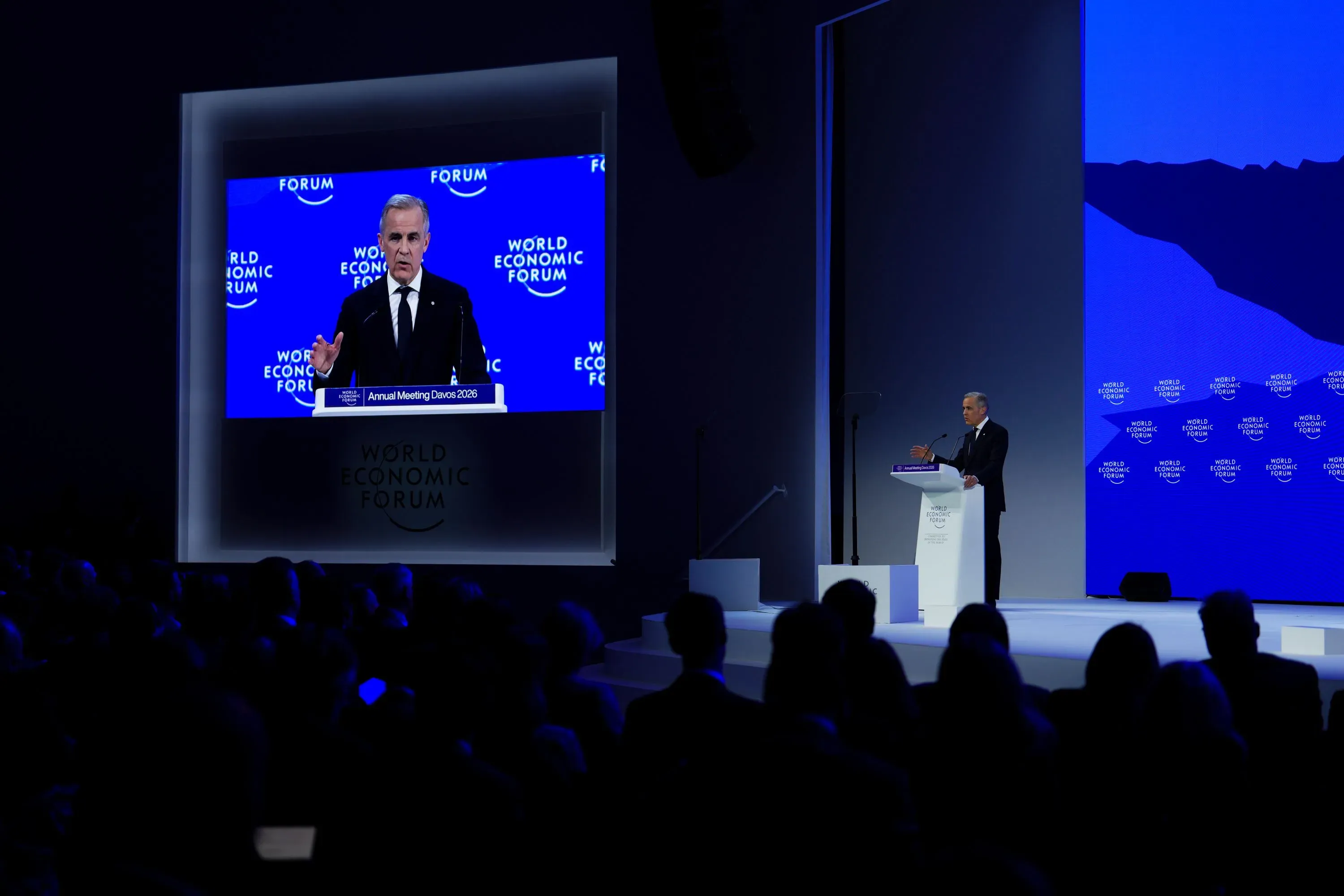 رئيس الوزراء الكندي مارك كارني يتحدث في المنتدى الاقتصادي العالمي في دافوس، مع خلفية تحمل شعار المنتدى، وسط جمهور كبير.