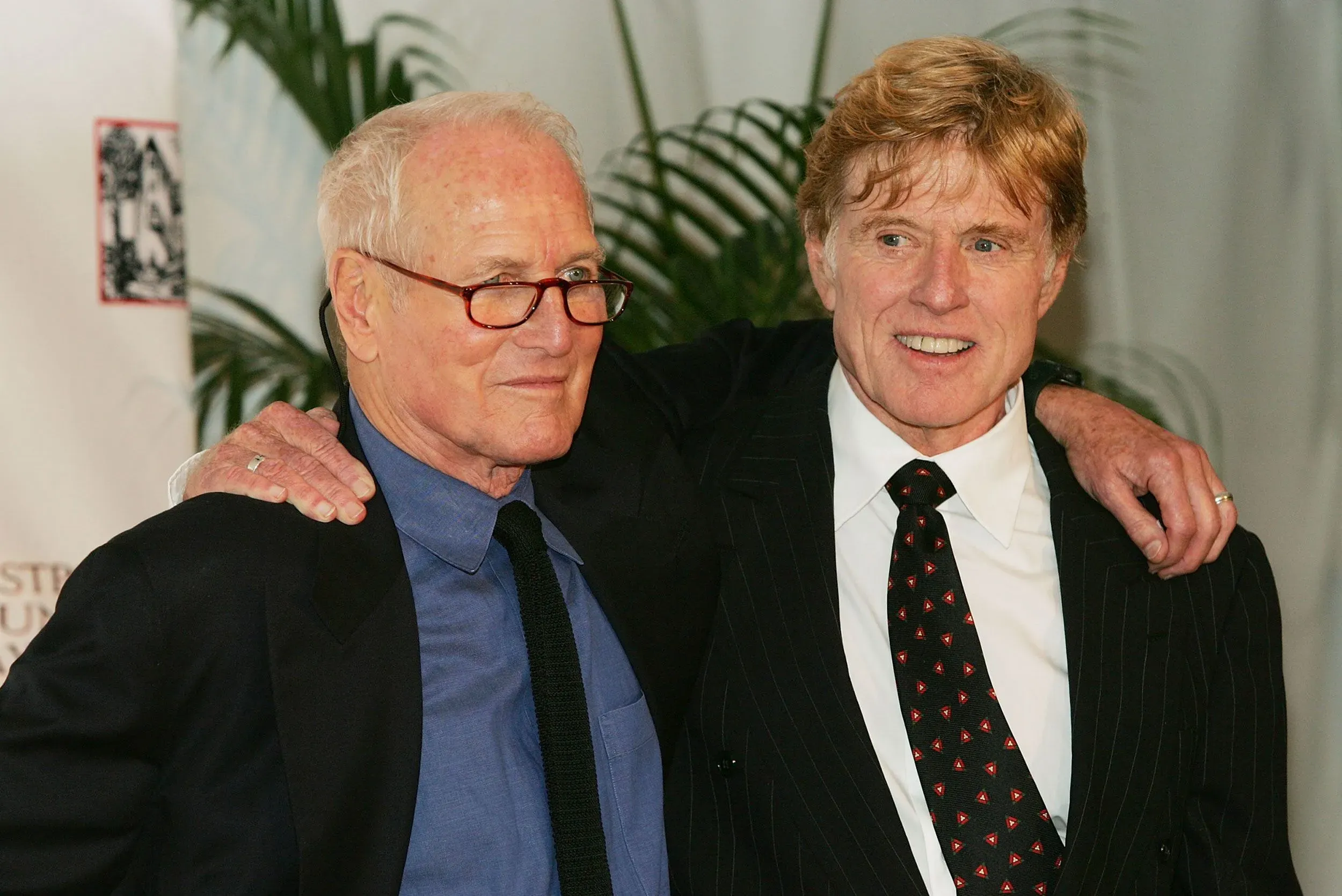 صورة لروبرت ريدفورد وبول نيومان، وهما يتبادلان الابتسامات في مناسبة عامة، تعكس صداقتهما الطويلة والمهنية في السينما.