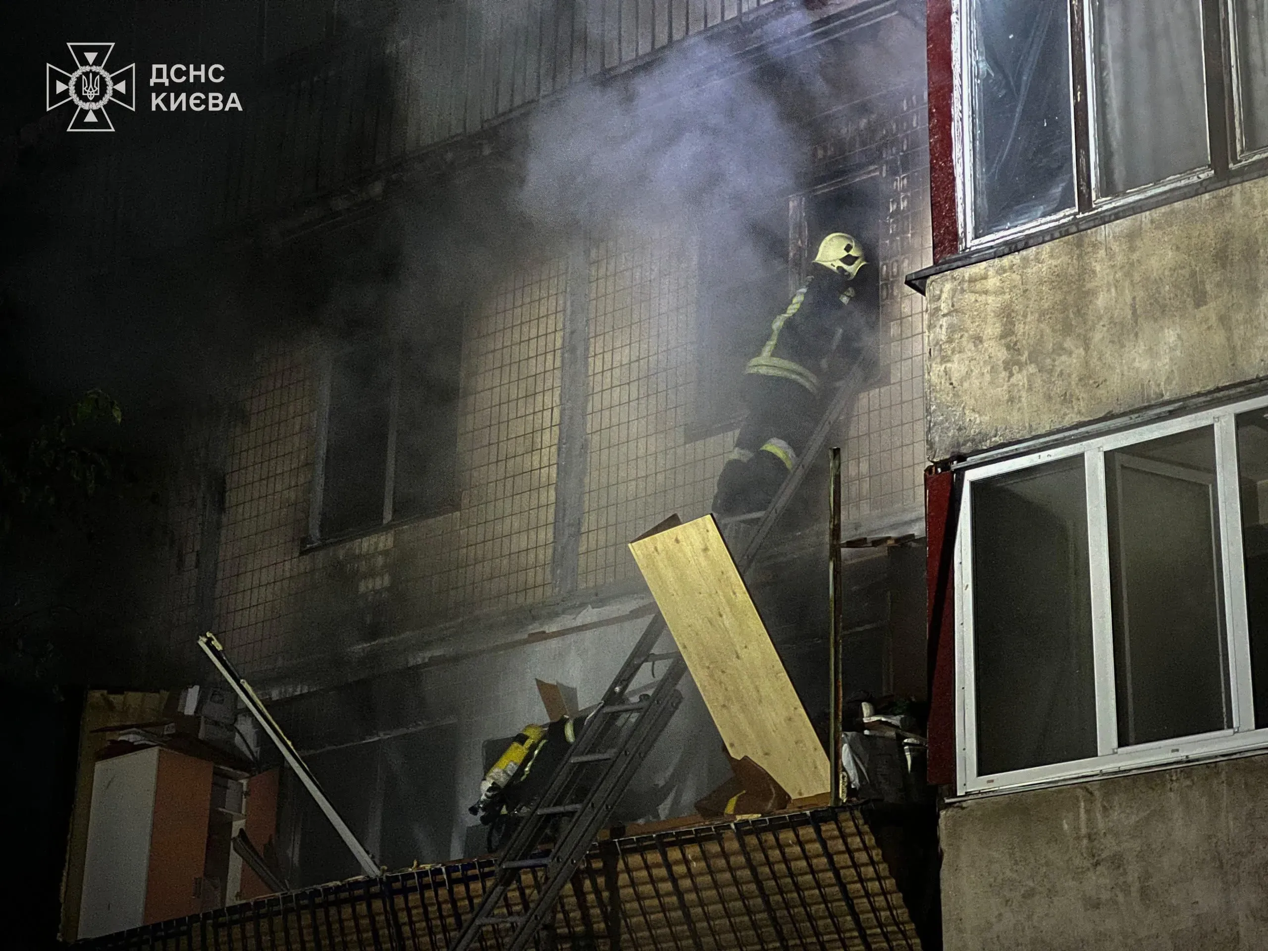 رجال الإطفاء يتسلقون سلمًا لإنقاذ الأشخاص من مبنى محترق في كييف، مع تصاعد الدخان من النوافذ بعد غارات جوية روسية.