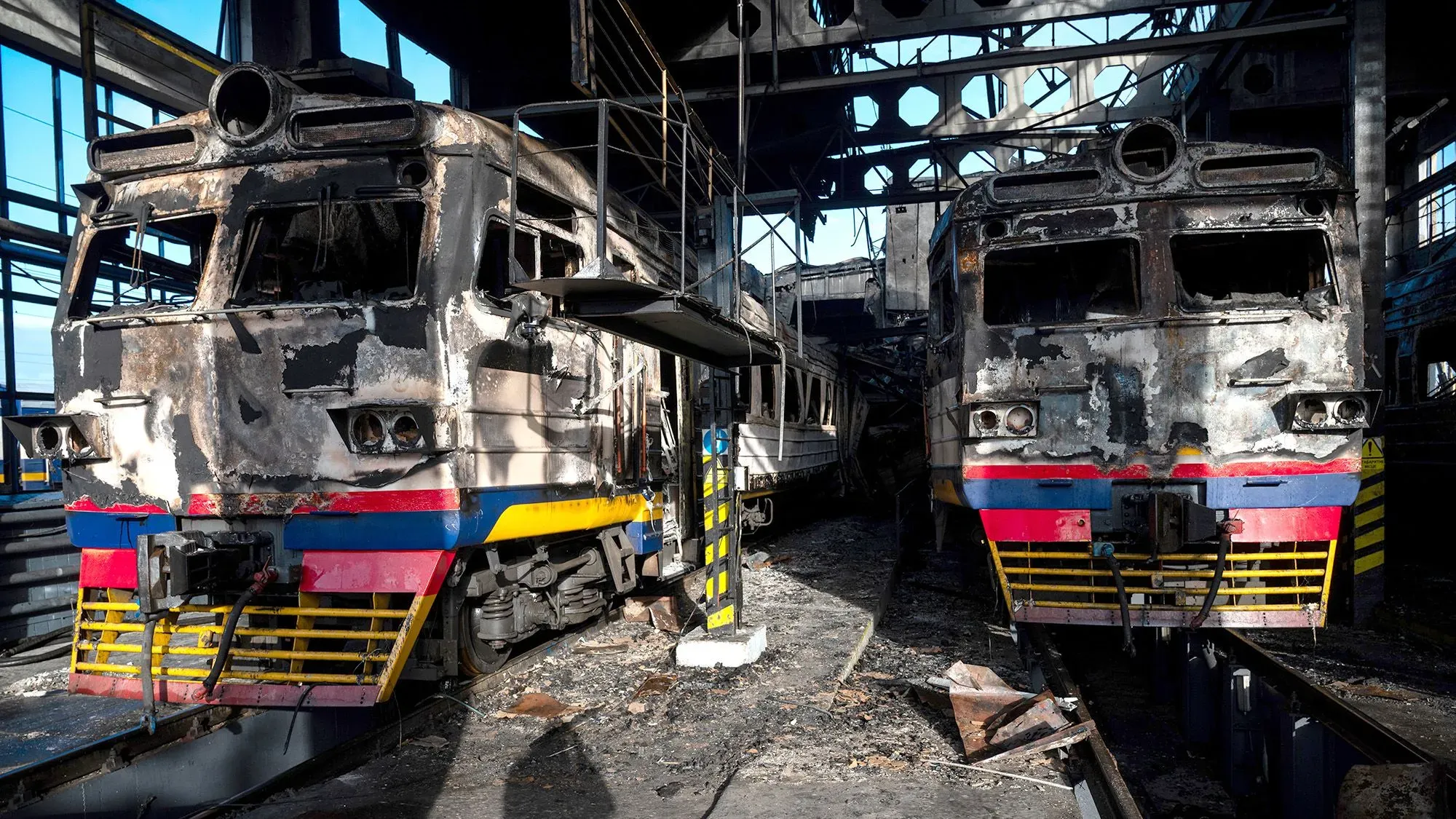 قطارات محترقة في ورشة صيانة أوكرانية، تعكس الأضرار التي لحقت بالبنية التحتية للسكك الحديدية بسبب الهجمات الروسية خلال الحرب.