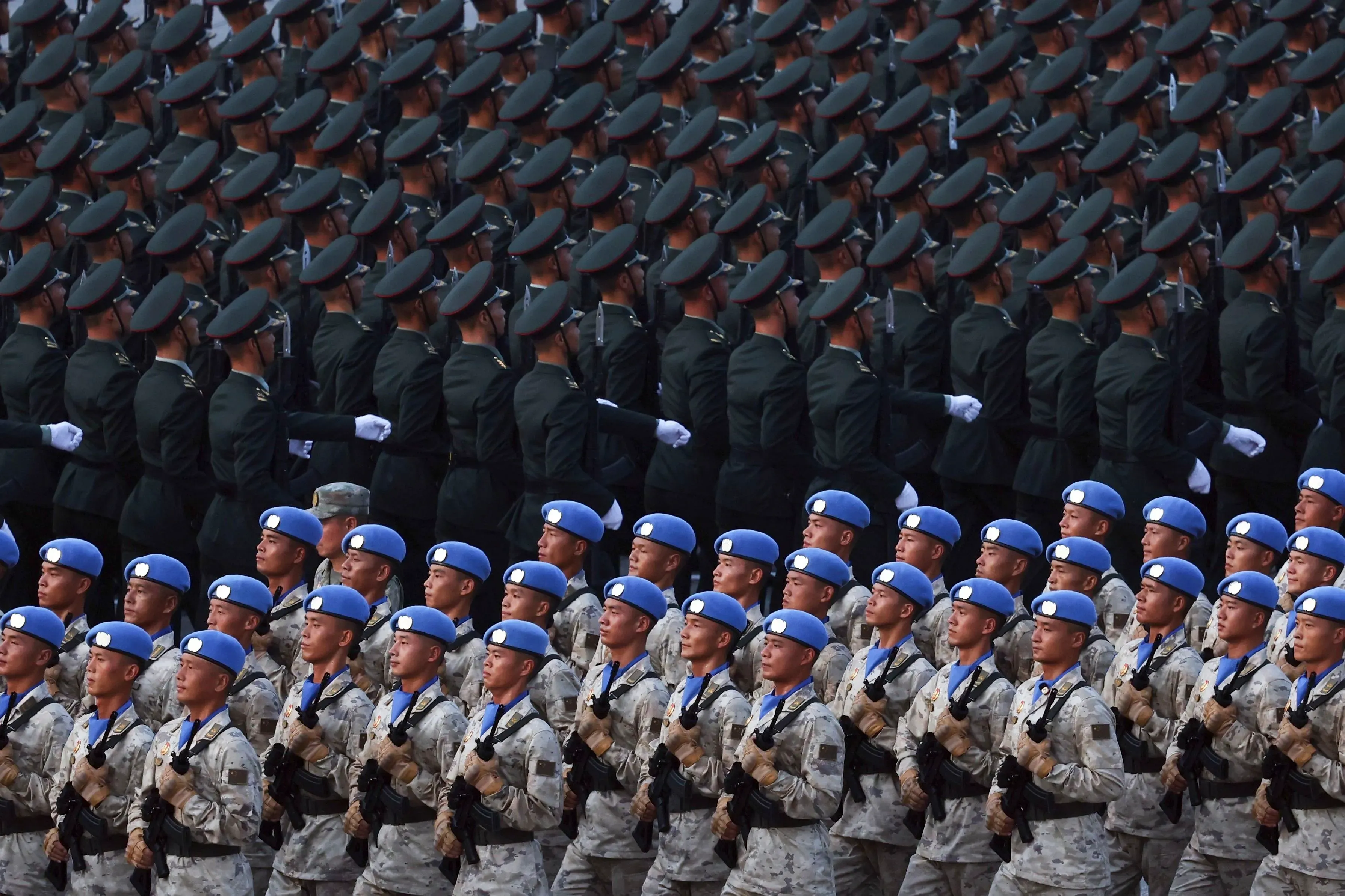 جنود من جيش التحرير الشعبي الصيني يرتدون زيًا عسكريًا مختلفًا، يشاركون في عرض عسكري، مما يعكس التعاون العسكري المتزايد مع روسيا.