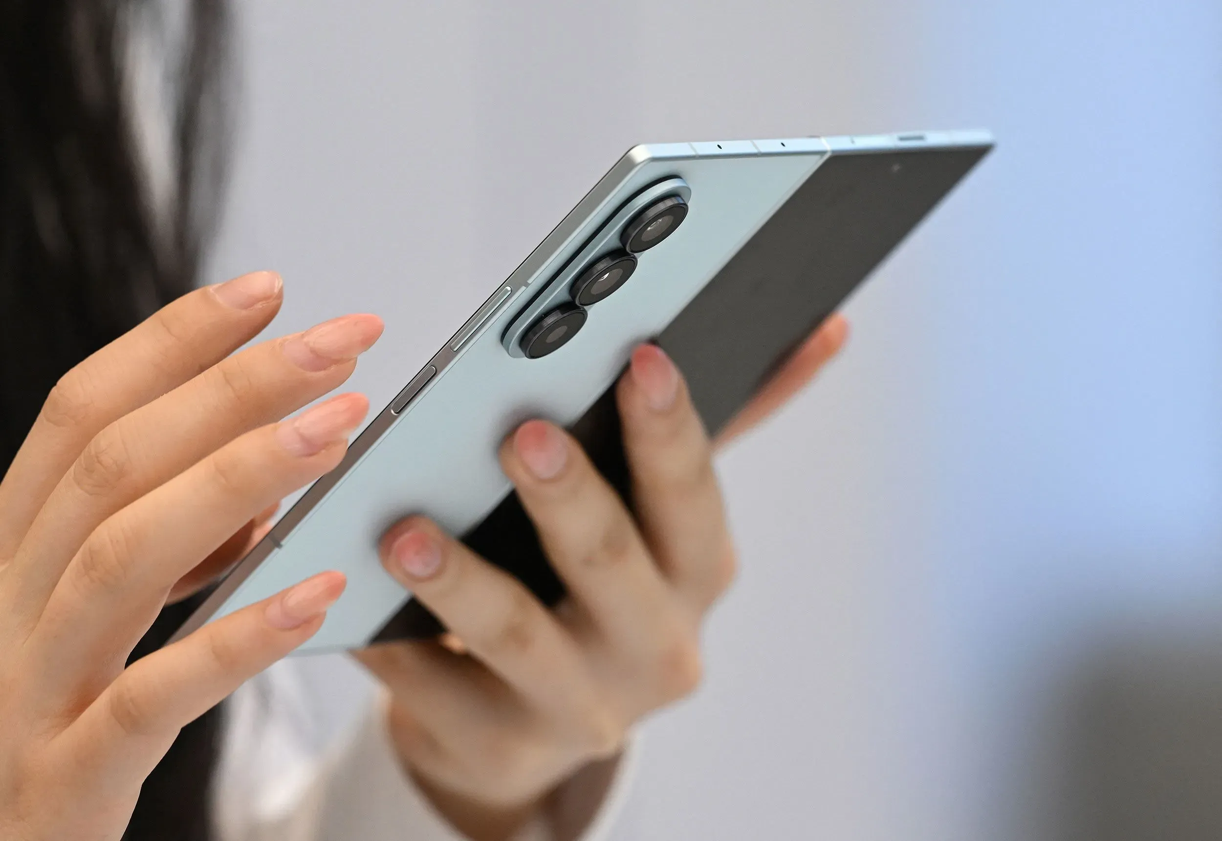 هاتف ذكي ثلاثي الطيات في يد امرأة، يعكس الابتكار في تصميم الهواتف القابلة للطي، مما يعزز تجربة المستخدم.