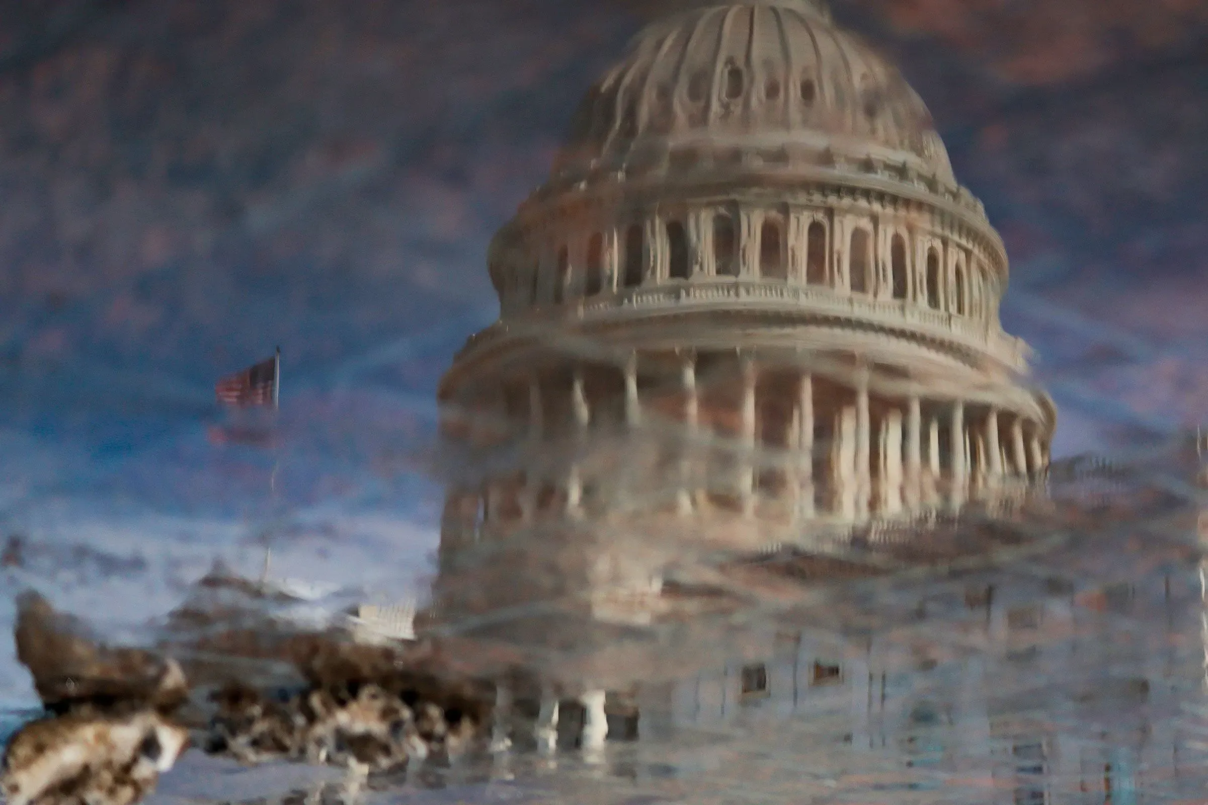 تظهر الصورة مبنى الكابيتول الأمريكي مع انعكاسه في بركة مياه، مما يرمز إلى القضايا المتعلقة بتداول الأسهم من قبل أعضاء الكونغرس.